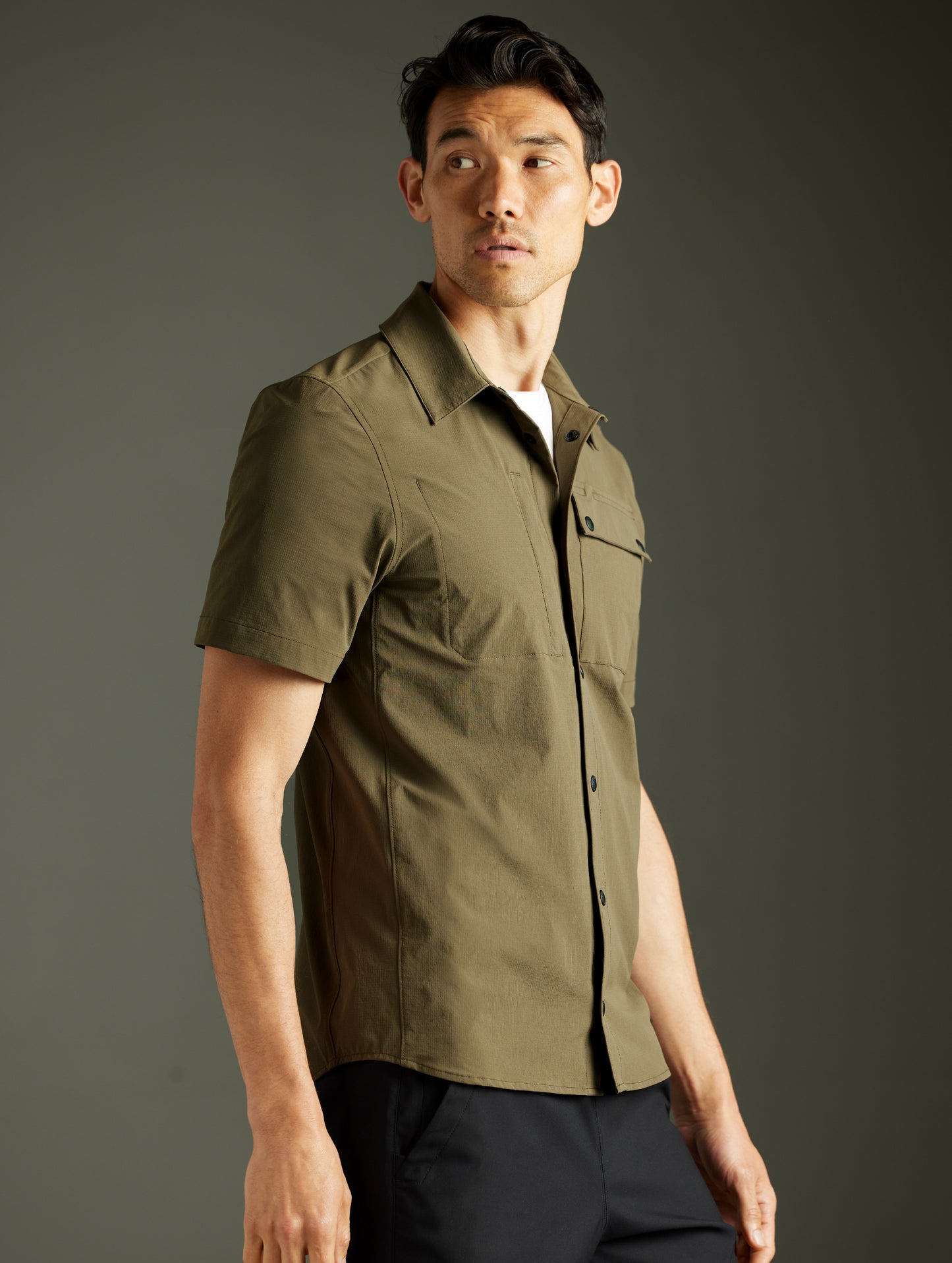 Front 3/4 body view of man wearing Wonder Technical Short-Sleeve Button-Down in Cadet green from AETHER Apparel.