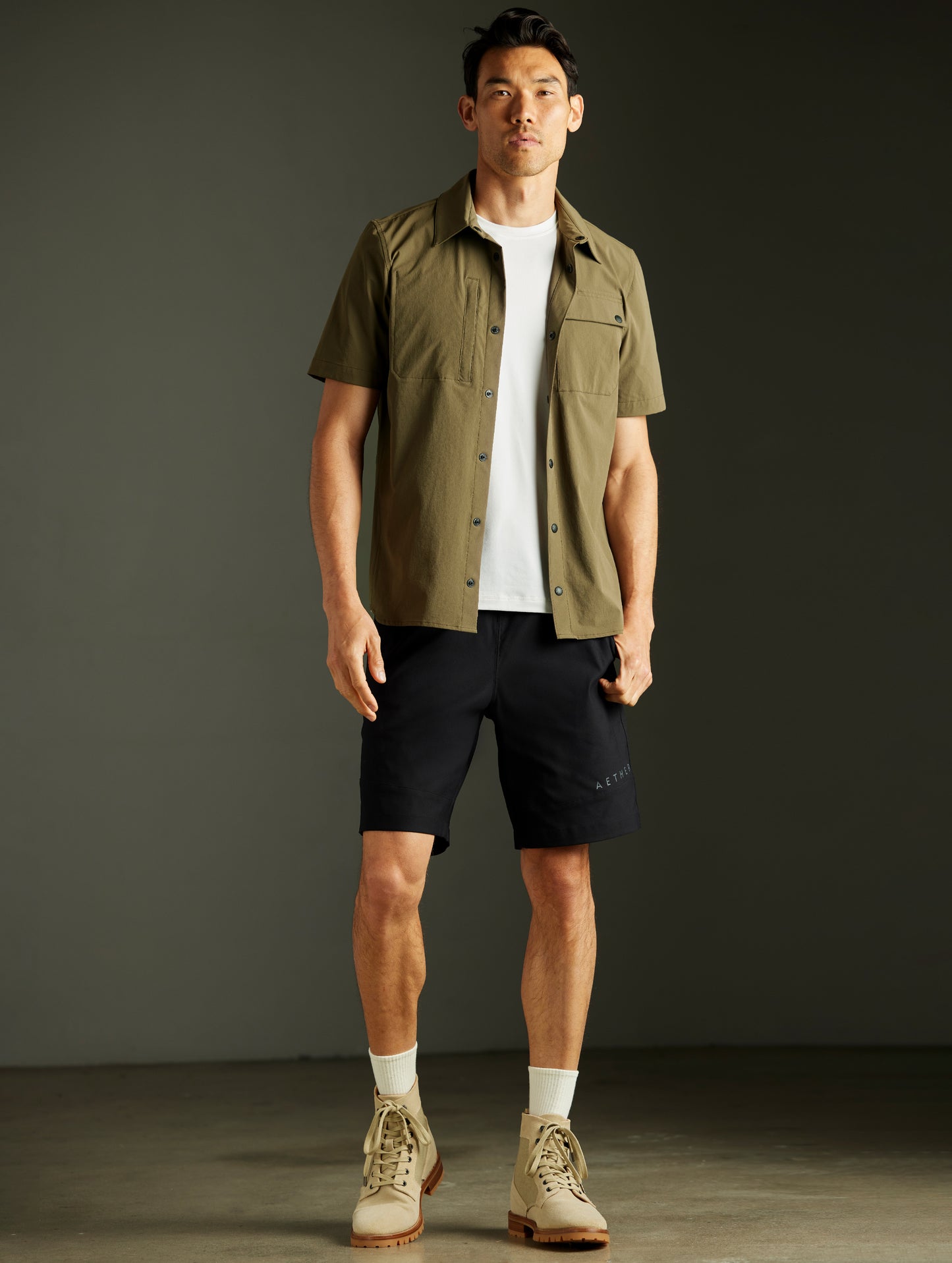 Front full-body view of man wearing Wonder Technical Short-Sleeve Button-Down in Cadet green from AETHER Apparel.