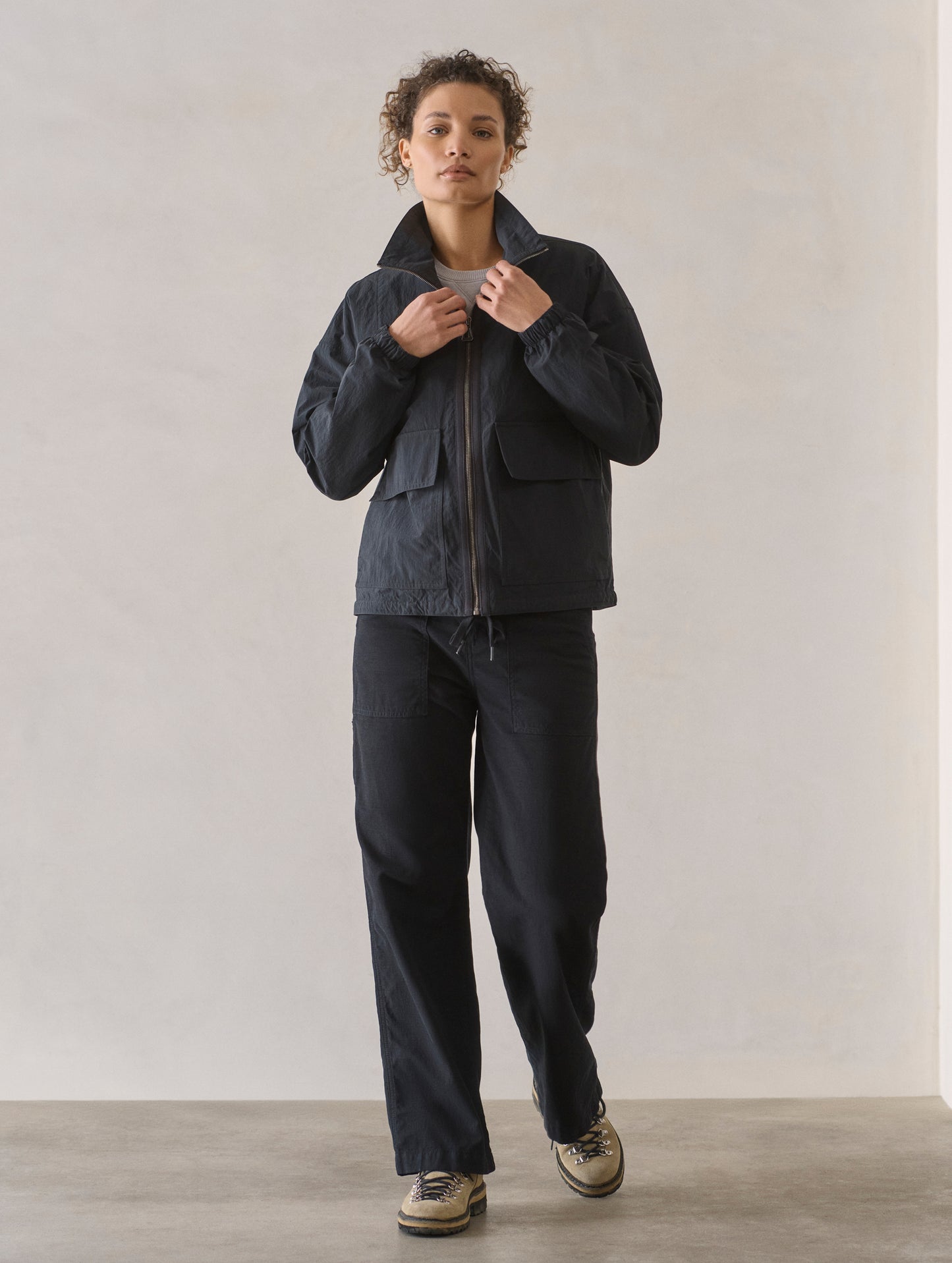 Front full-body view of woman wearing Mila Windbreaker in Onyx Black from AETHER Apparel.