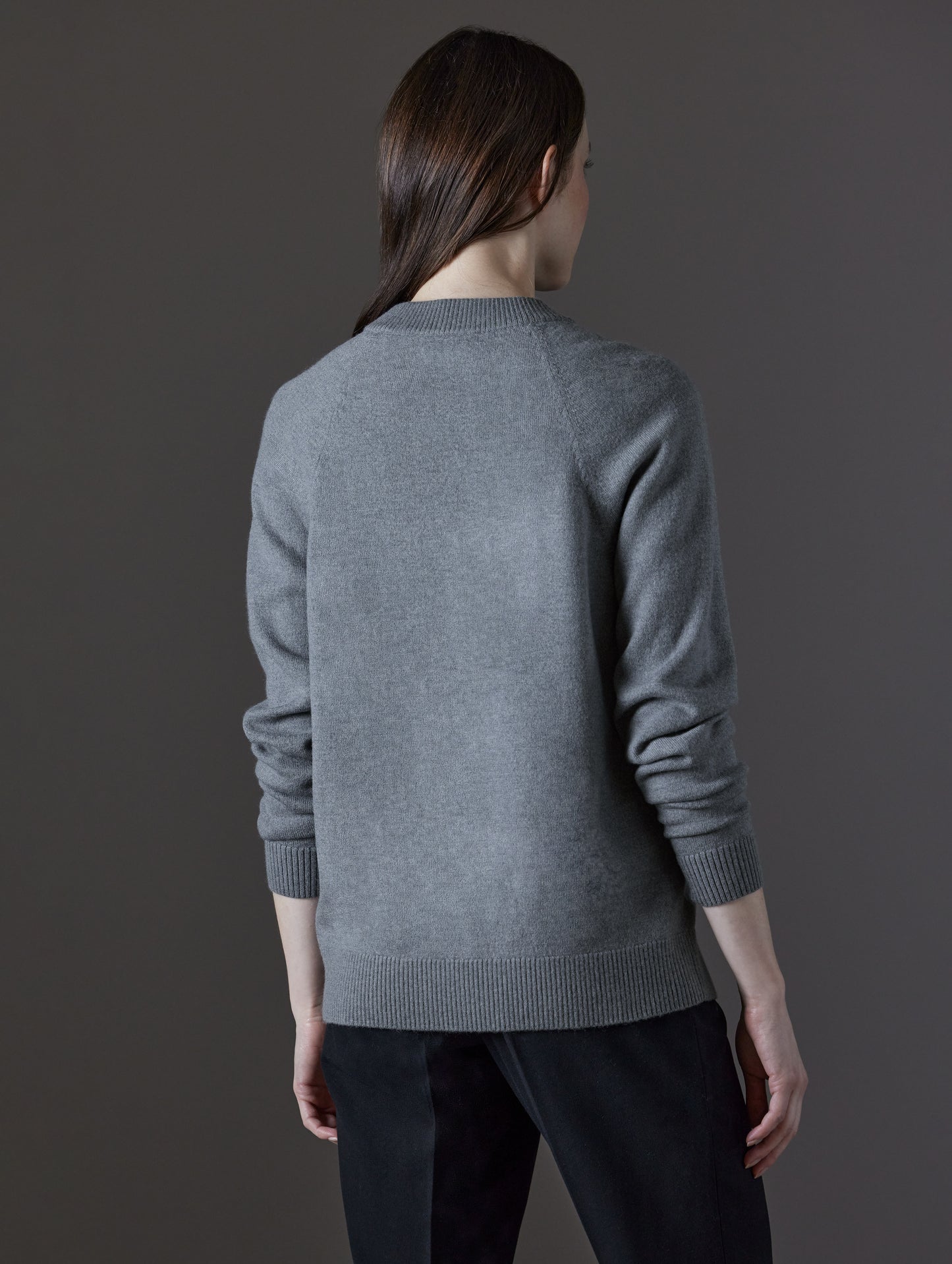 Rear angled view of woman wearing Mosie Sweater in Light Heather Grey from AETHER Apparel.