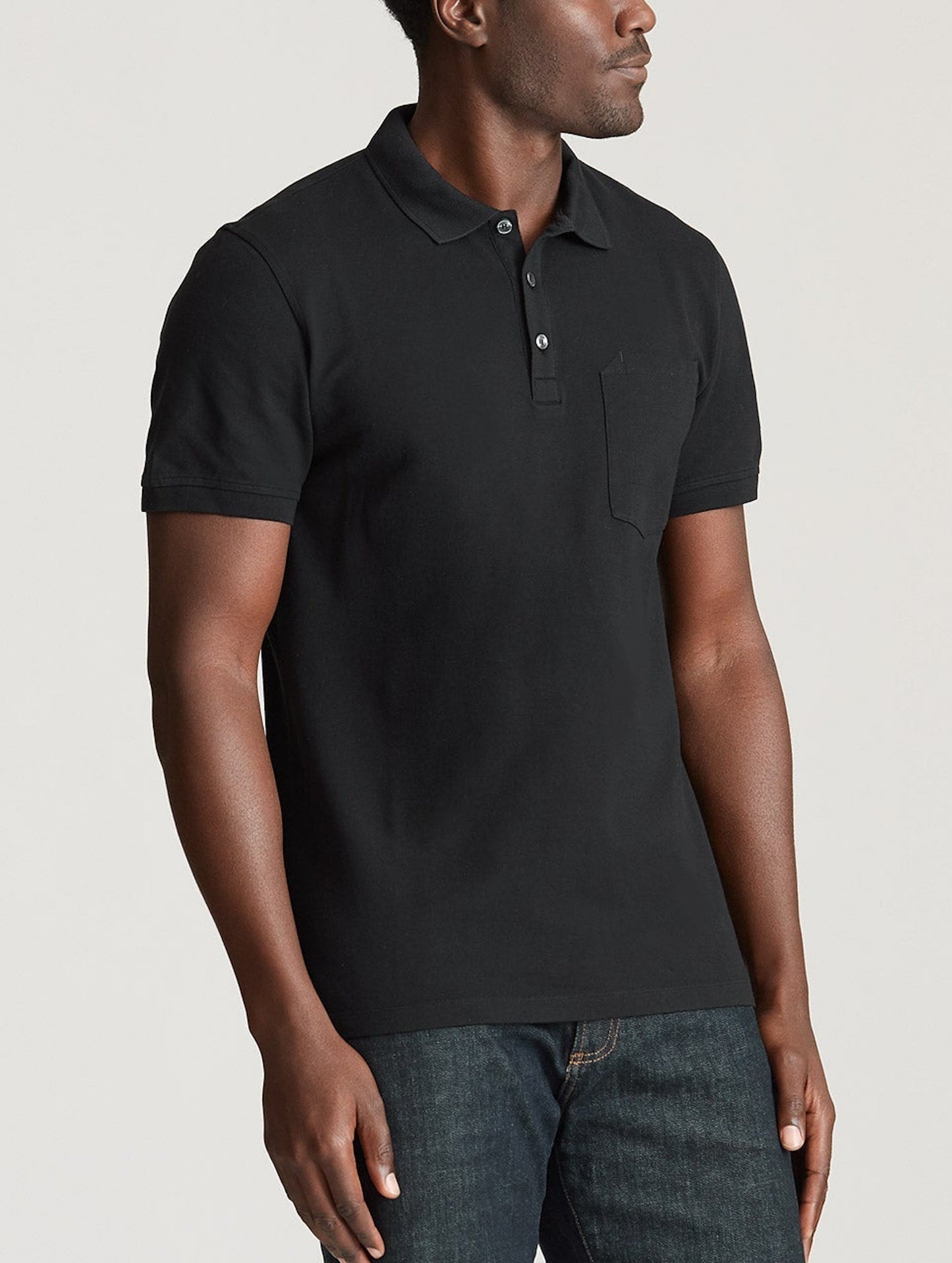 Upper body view of man wearing black Pique Polo from AETHER Apparel.