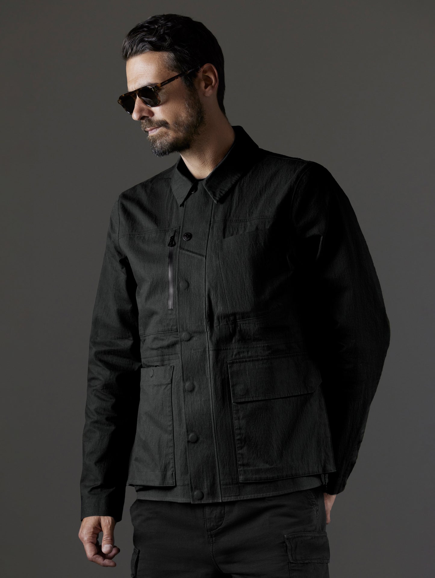Front 3/4 upper body view of man wearing AETHER + LEICA Reporter Jacket in Monochrom.