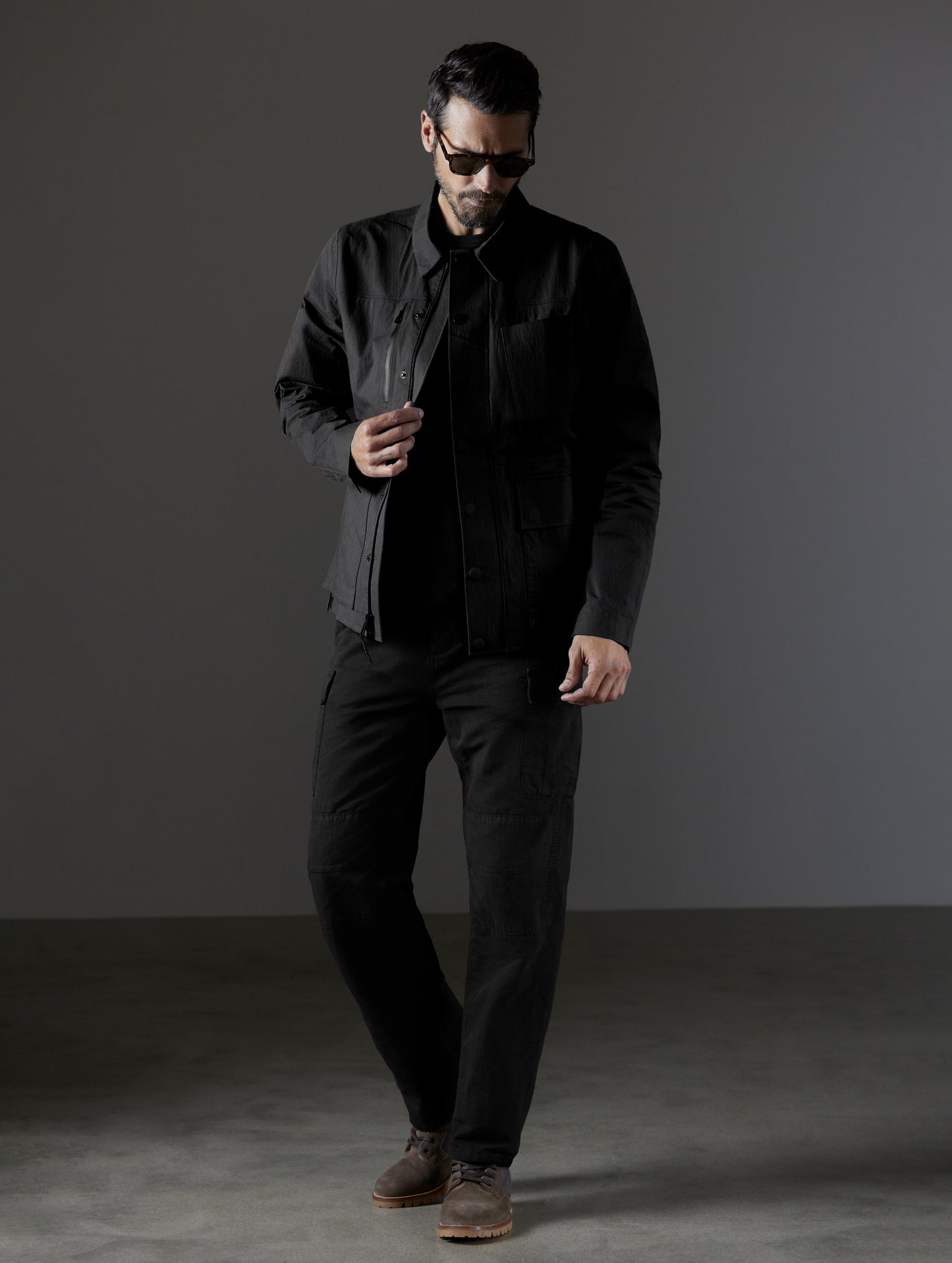 Front full body view of man wearing AETHER + LEICA Reporter Jacket in Monochrom.