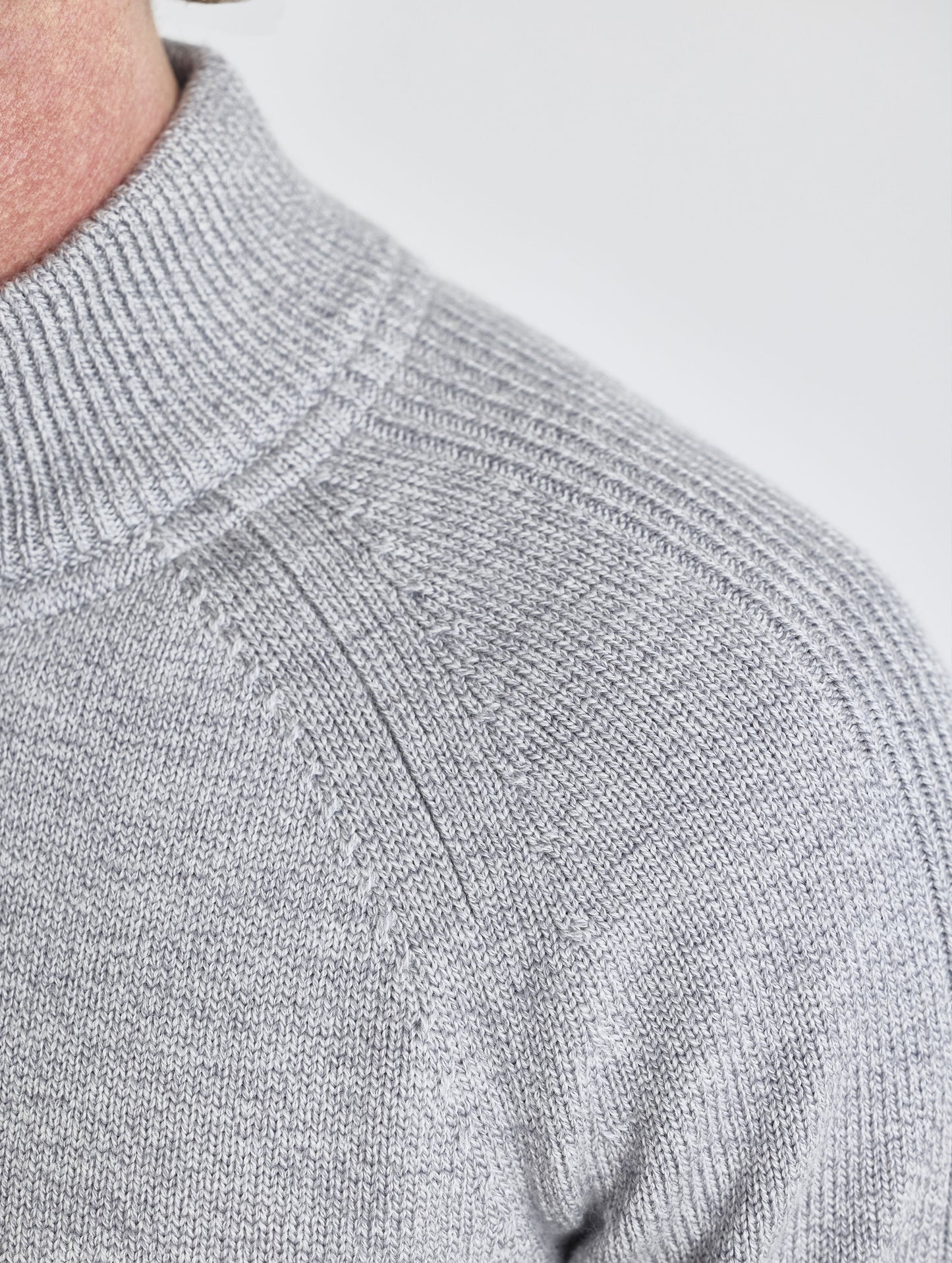 Closeup detail view of wearer's left shoulder stitch of Riley Full-Zip Sweater in Light Heather Grey from AETHER Apparel.