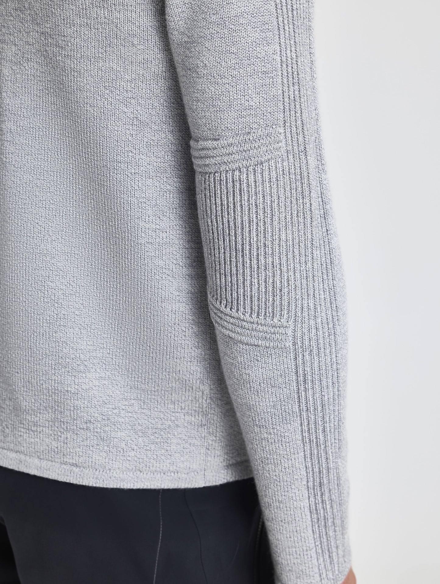 Closeup rear detail view of wearer's right sleeve patch of Riley Full-Zip Sweater in Light Heather Grey from AETHER Apparel.