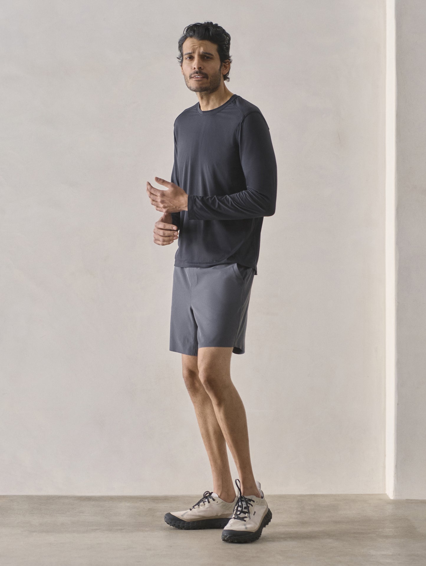 Front 3/4 full-body view of man wearing Rogue Hybrid Short in Graphite from AETHER Apparel.