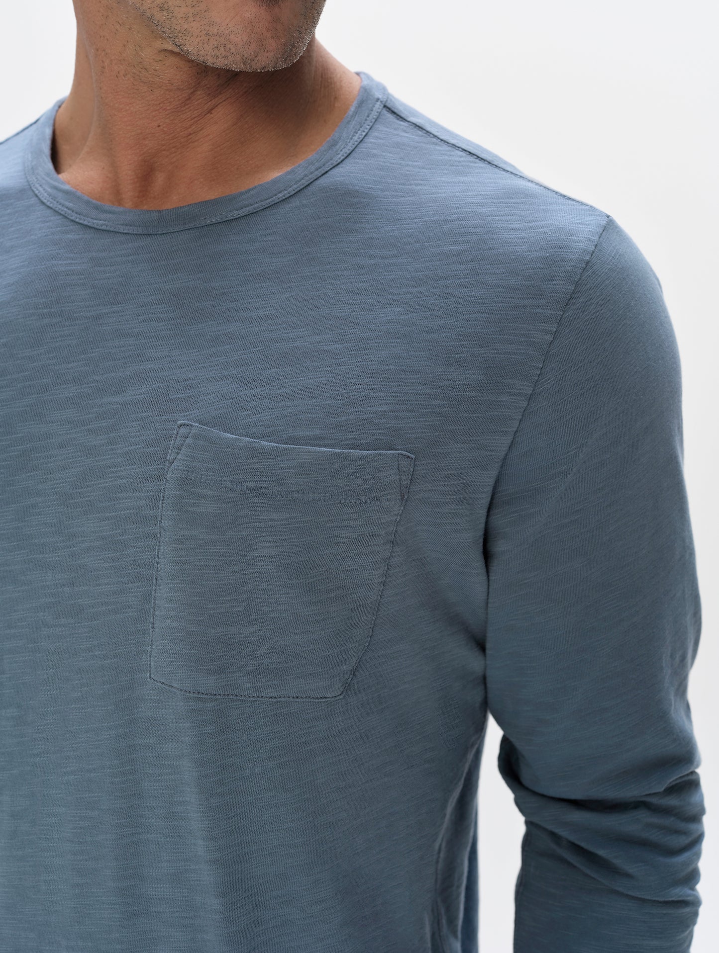 Closeup detailed view of the shoulder and patch pocket on the Slub Pocket Long-Sleeve Tee 2.0 in Portal Blue from AETHER Apparel.