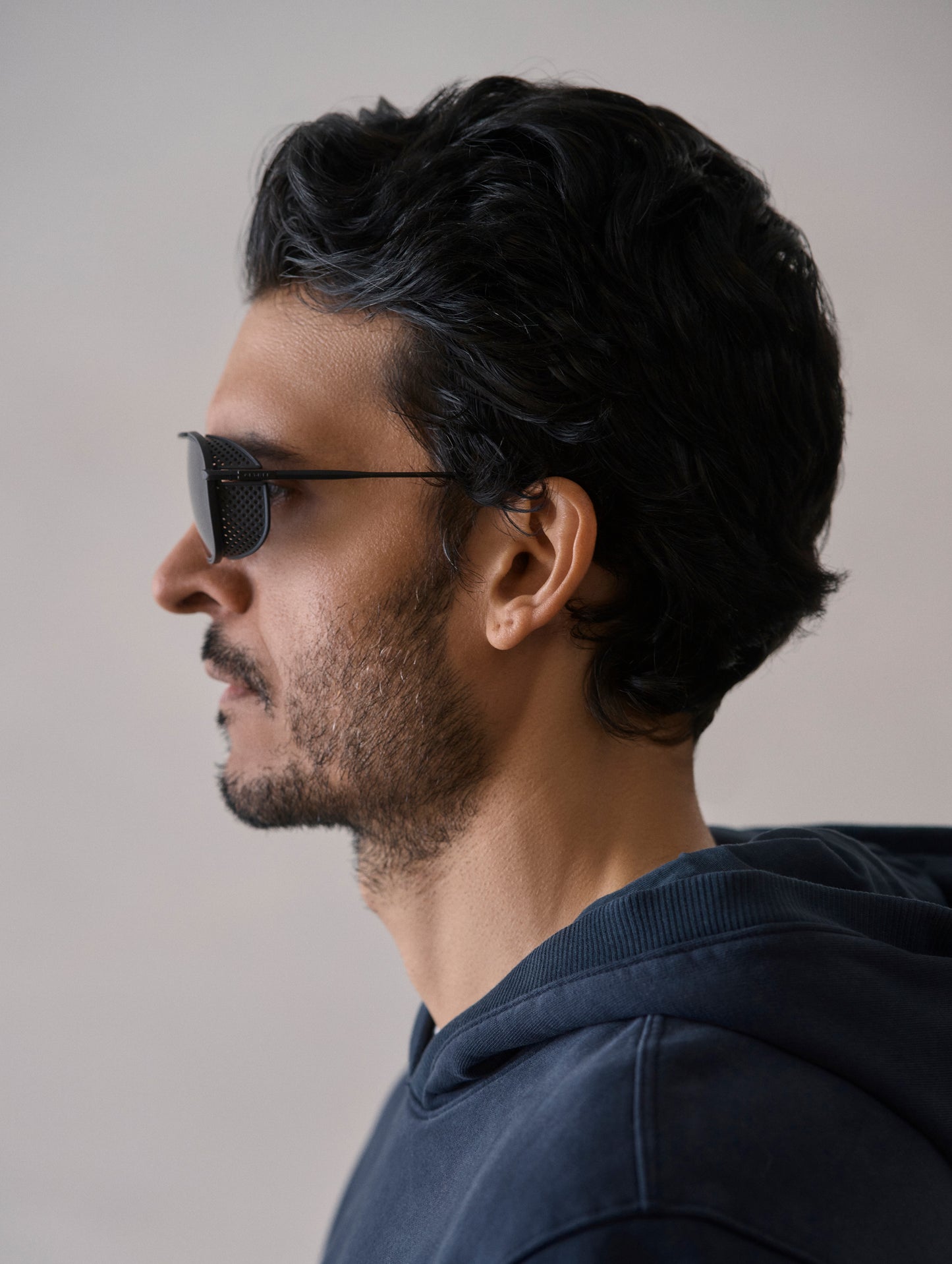 Side profile view of man wearing Summit Sunglass in Black titanium with black lens from AETHER Apparel.