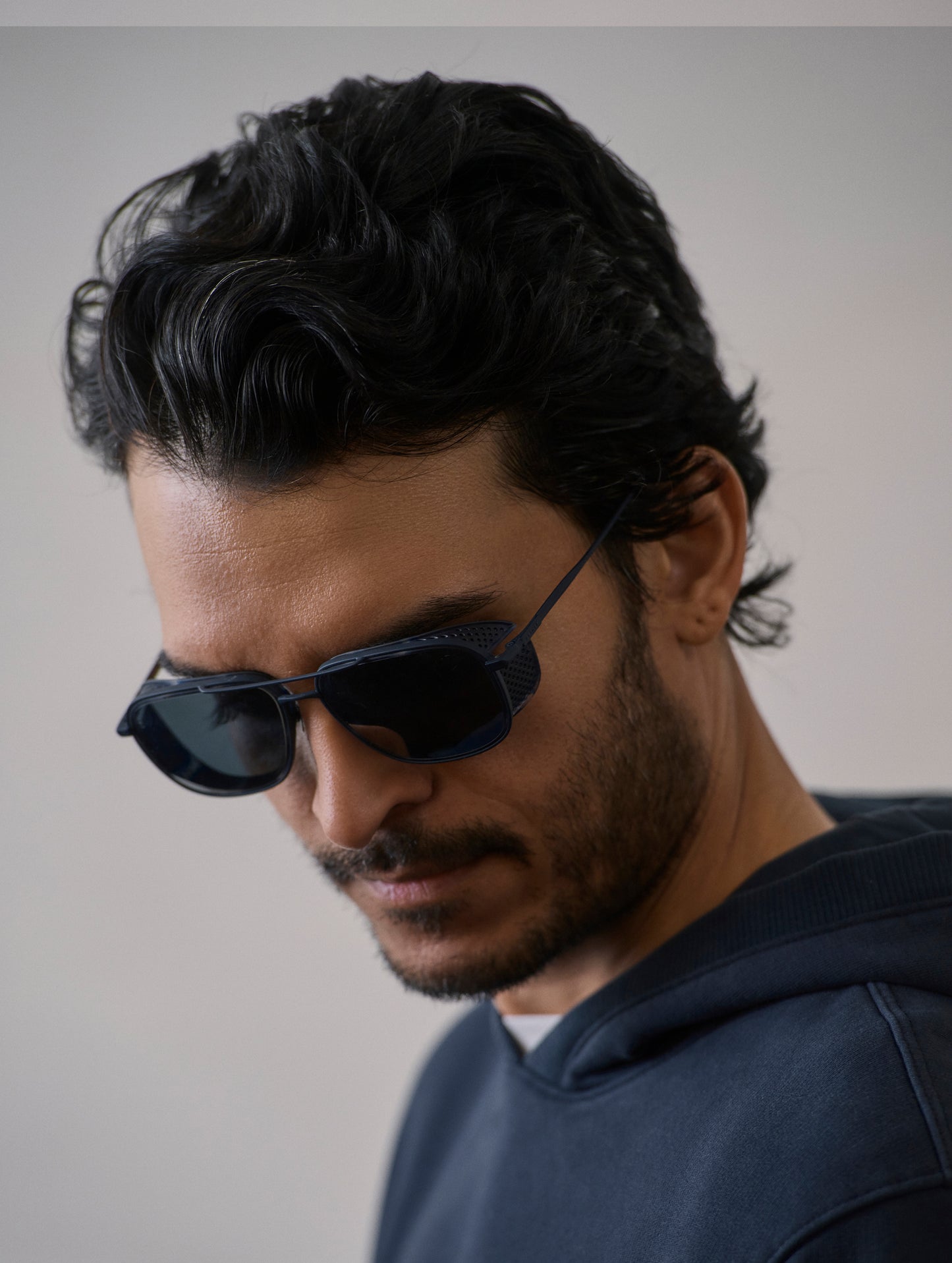 Front 3/4 view of man wearing Summit Sunglass in Blue titanium with Blue Lens from AETHER Apparel.