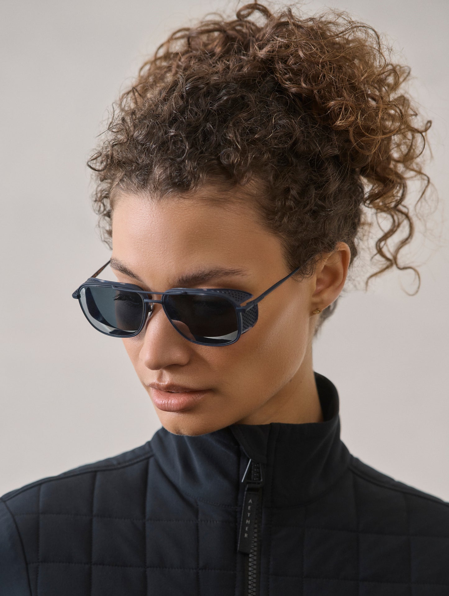 Front 3/4 view of woman wearing Summit Sunglass in Blue titanium with Blue Lens from AETHER Apparel.