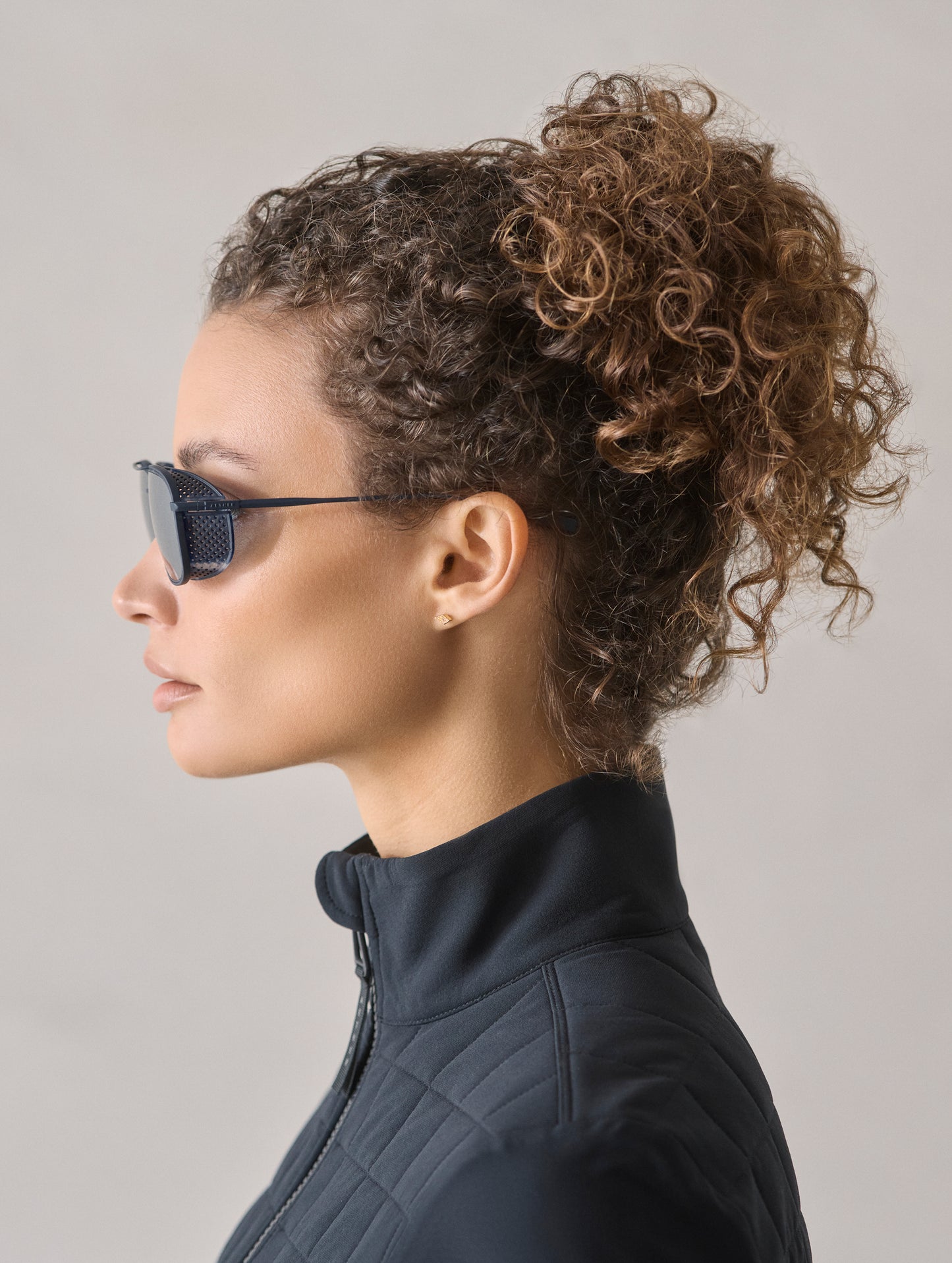 Side profile view of woman wearing Summit Sunglass in Blue titanium with Blue Lens from AETHER Apparel.