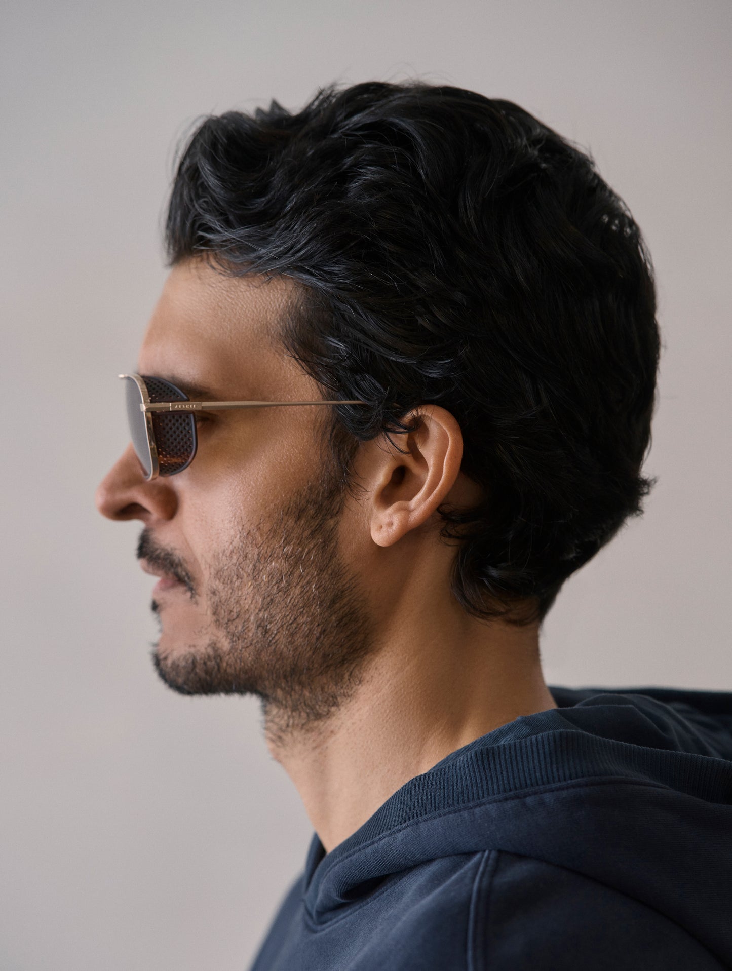 Side profile view of man wearing Summit Sunglass in Brushed Gold titanium with G15 Lens from AETHER Apparel.