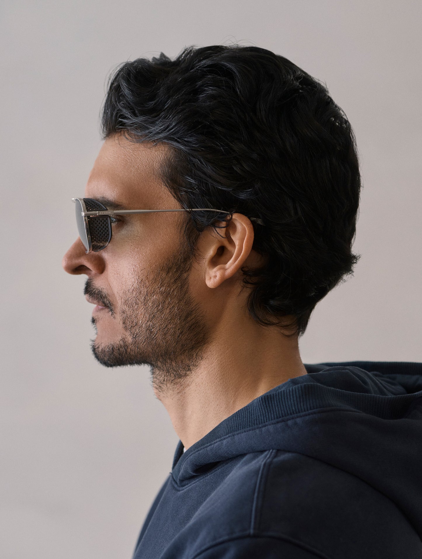 Side profile view of man wearing Summit Sunglass in Brushed Silver titanium with Grey Lens from AETHER Apparel.