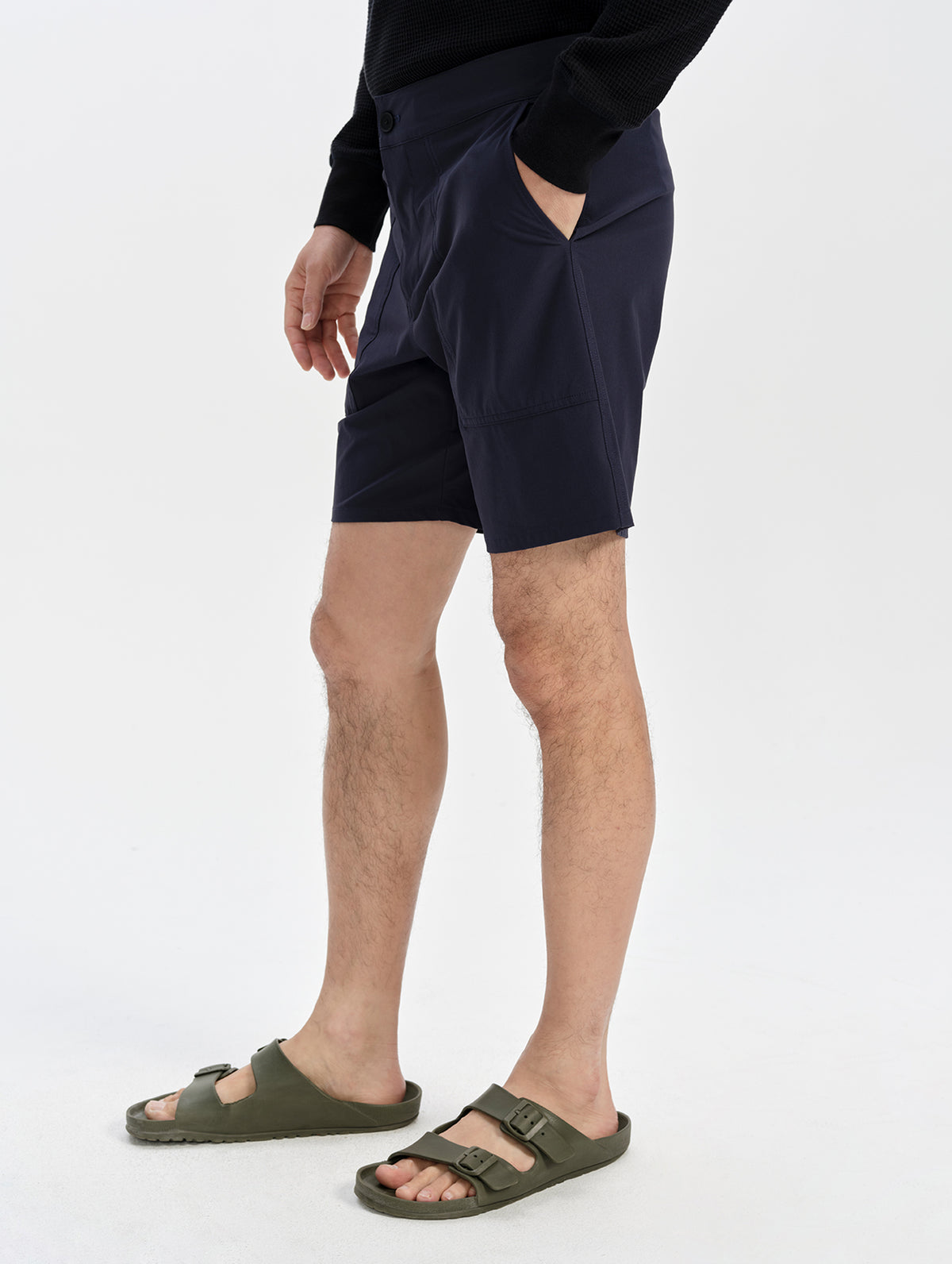 Lower-body side view of a model in the Velo Short in Total Eclipse, with a hand in the pocket, showing the above-knee fit.