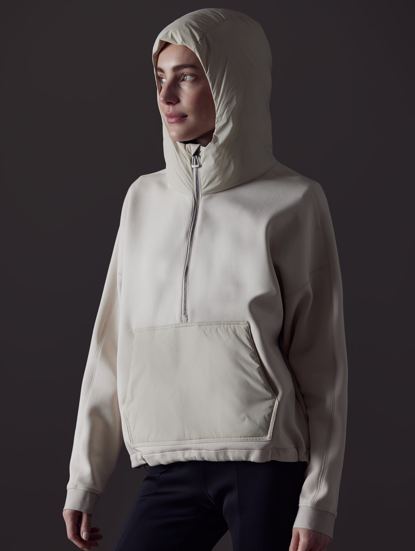 Front angled view of woman wearing Align Hooded Anorak in Bone white from AETHER Apparel with hood up.