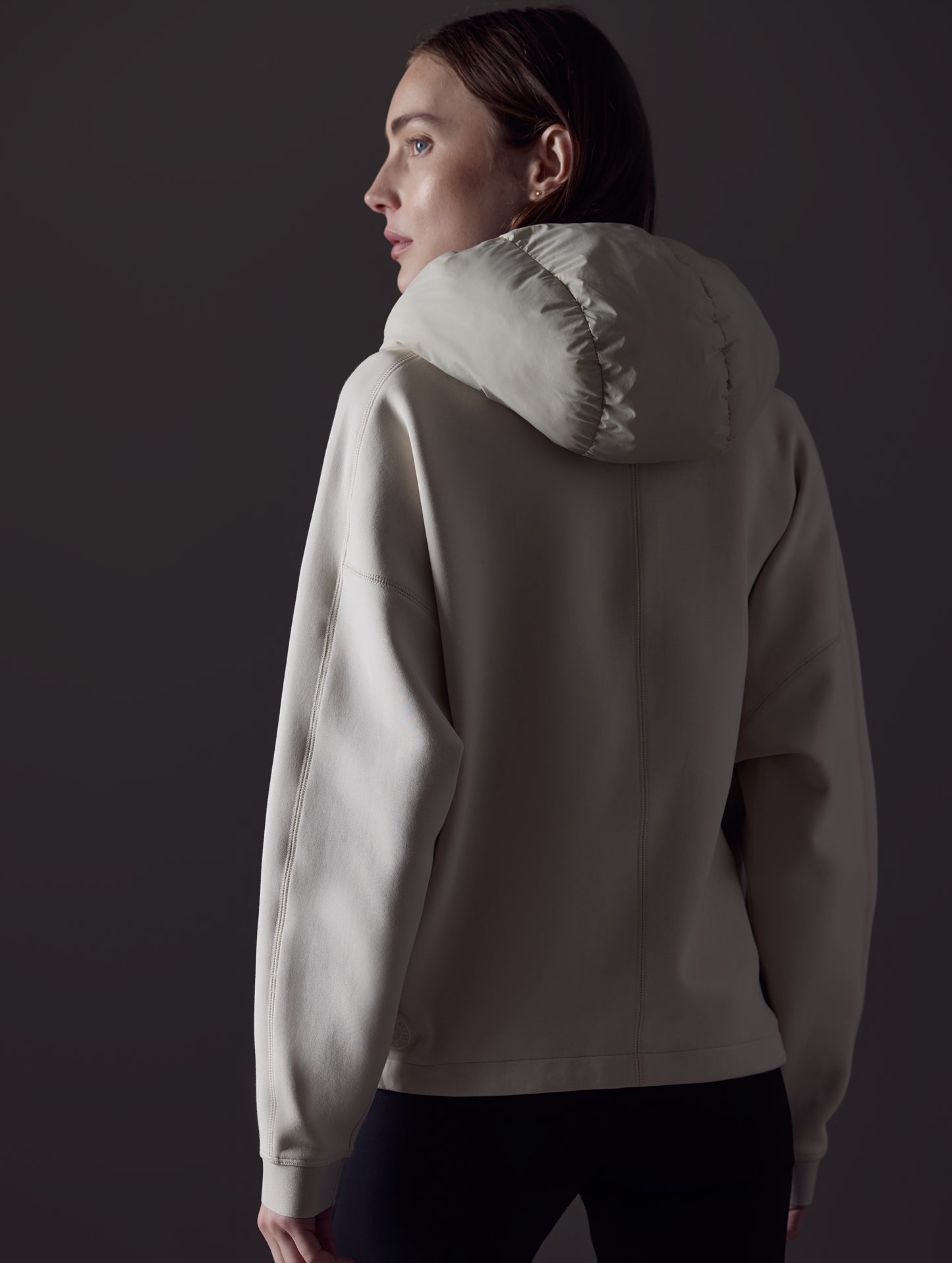 Rear angled view of woman wearing Align Hooded Anorak in Bone white from AETHER Apparel.