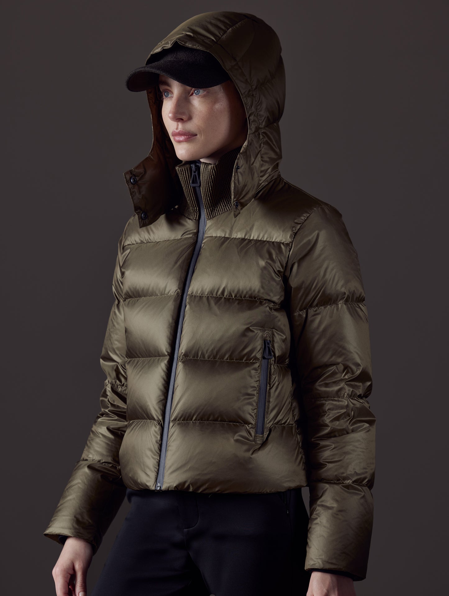 Front angled view of woman wearing Aura Puffer Jacket in Command Green from AETHER Apparel.