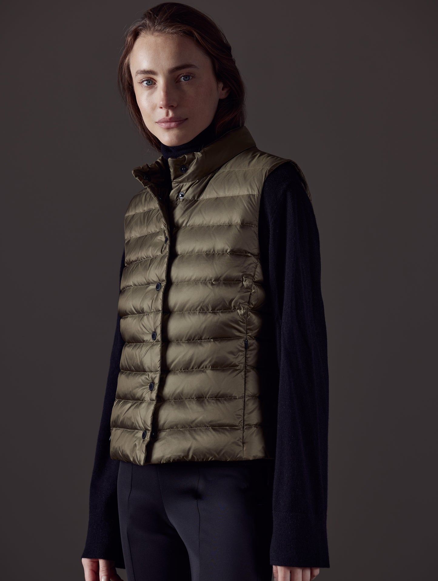 Front angled view of woman wearing Aura Vest in Command Green from AETHER Apparel.
