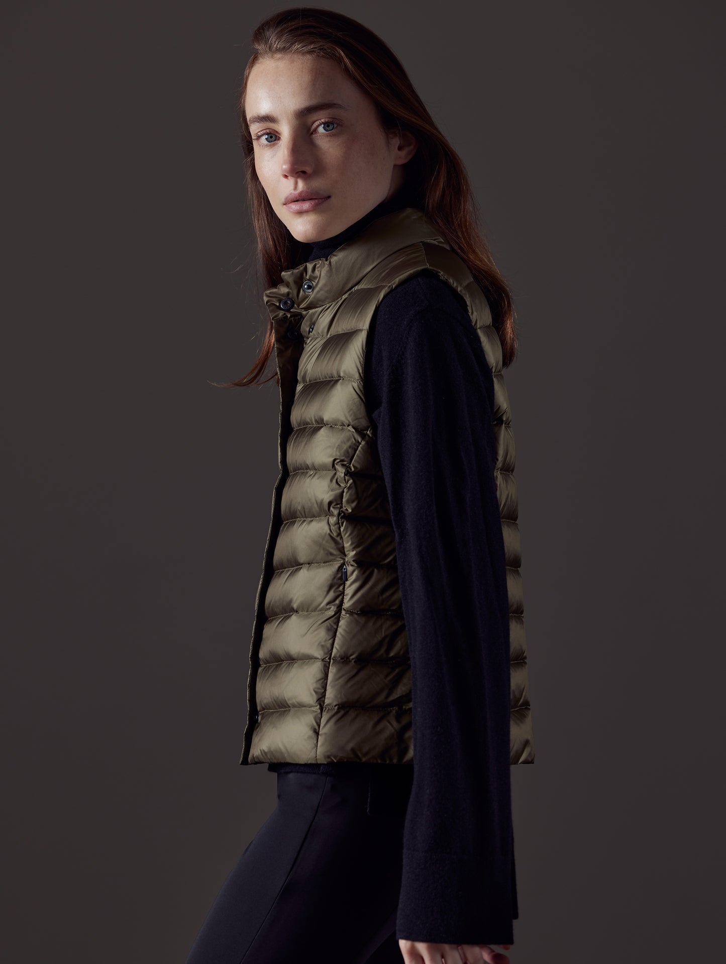 Side profile view of woman wearing Aura Vest in Command Green from AETHER Apparel.