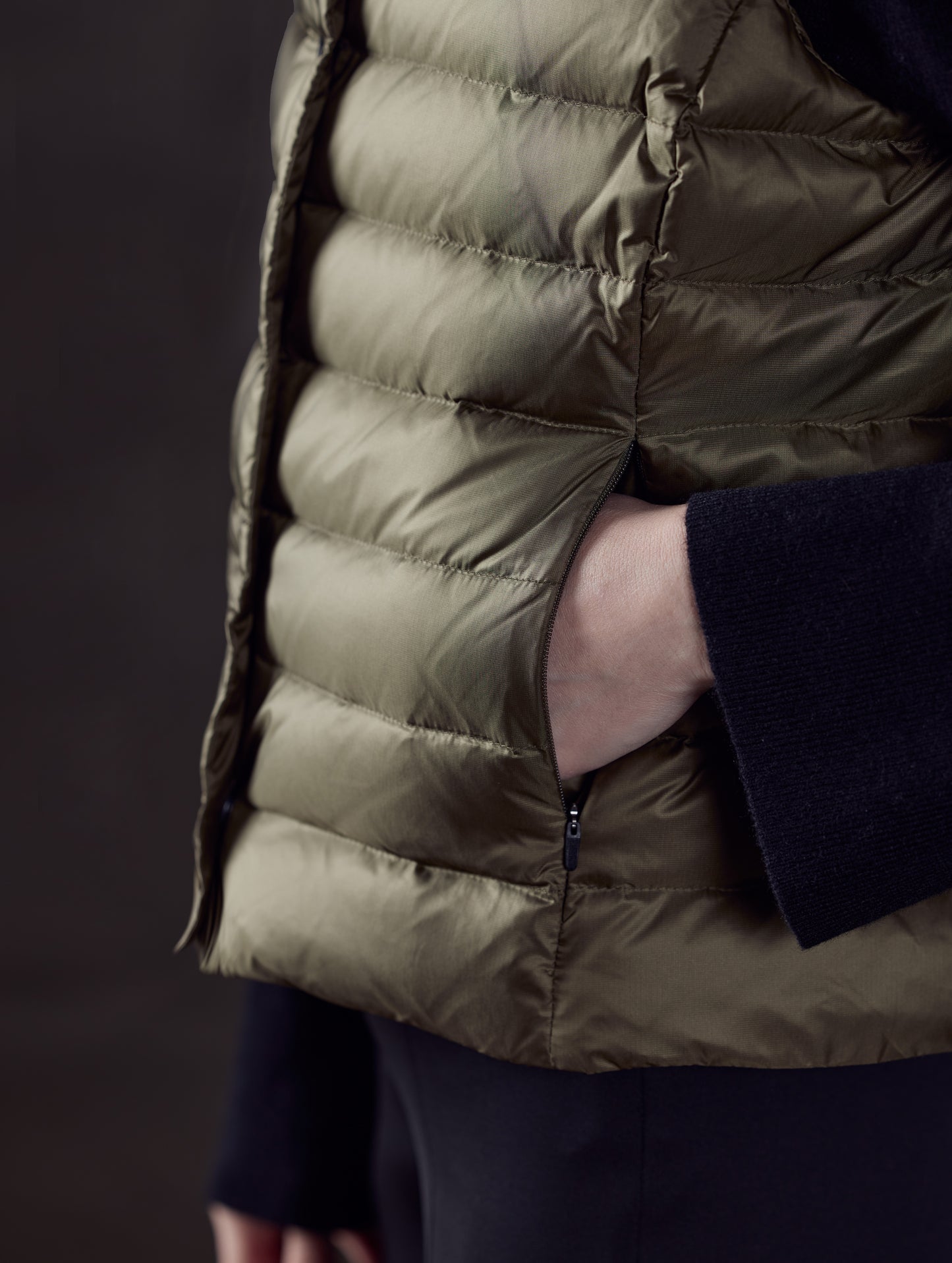Closeup detailed view of baffling and zippered hand pockets of Aura Vest in Command Green from AETHER Apparel.