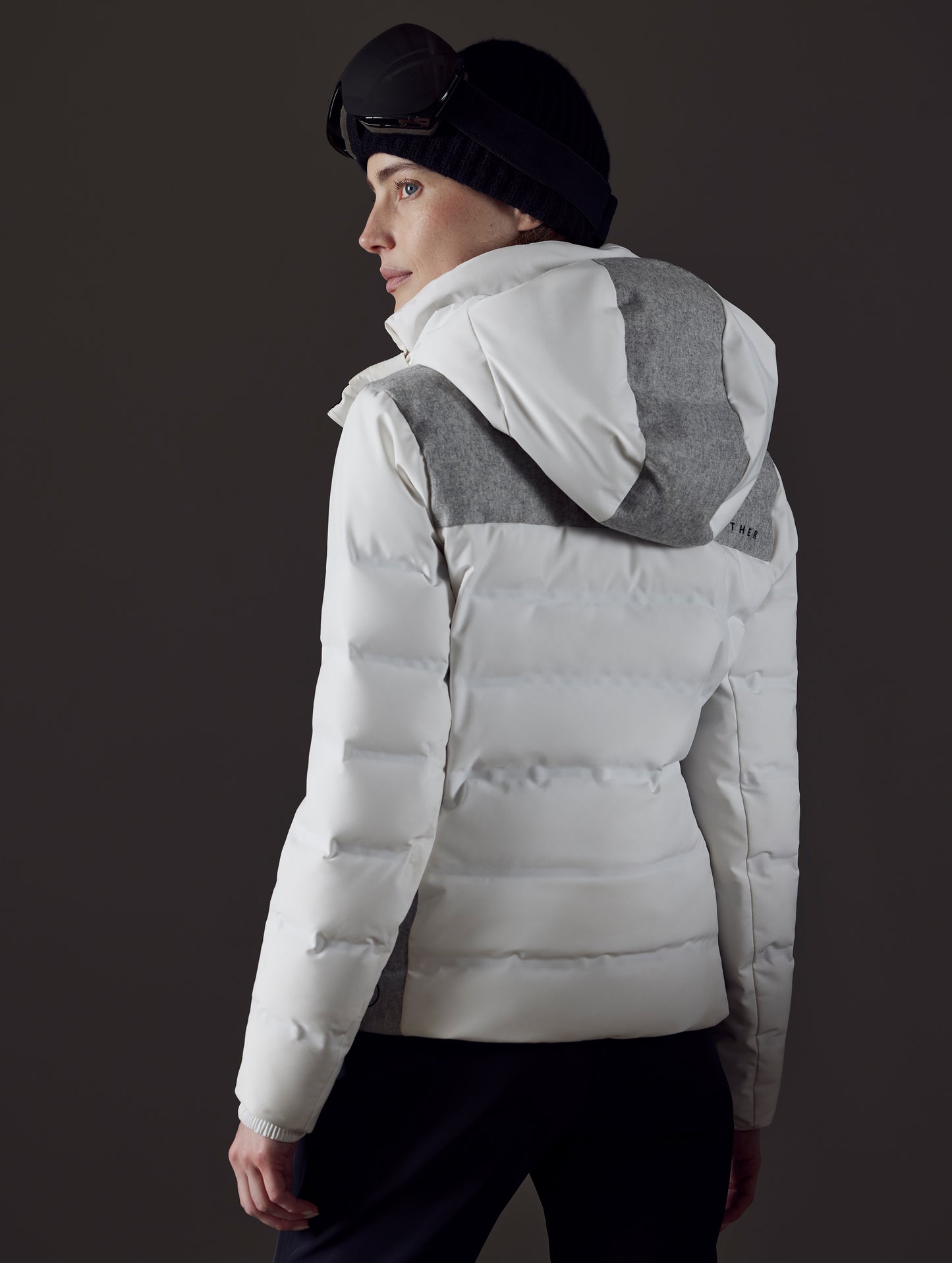 Rear angled view of woman wearing Bancroft Snow Jacket in White from AETHER Apparel.