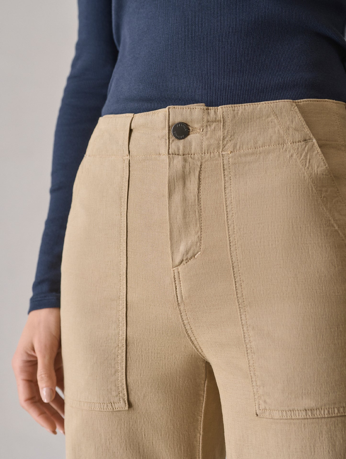 Closeup detailed view of the front closure and front field patch hand pockets on the Bella Travel Pant in Desert Tan from AETHER Apparel.