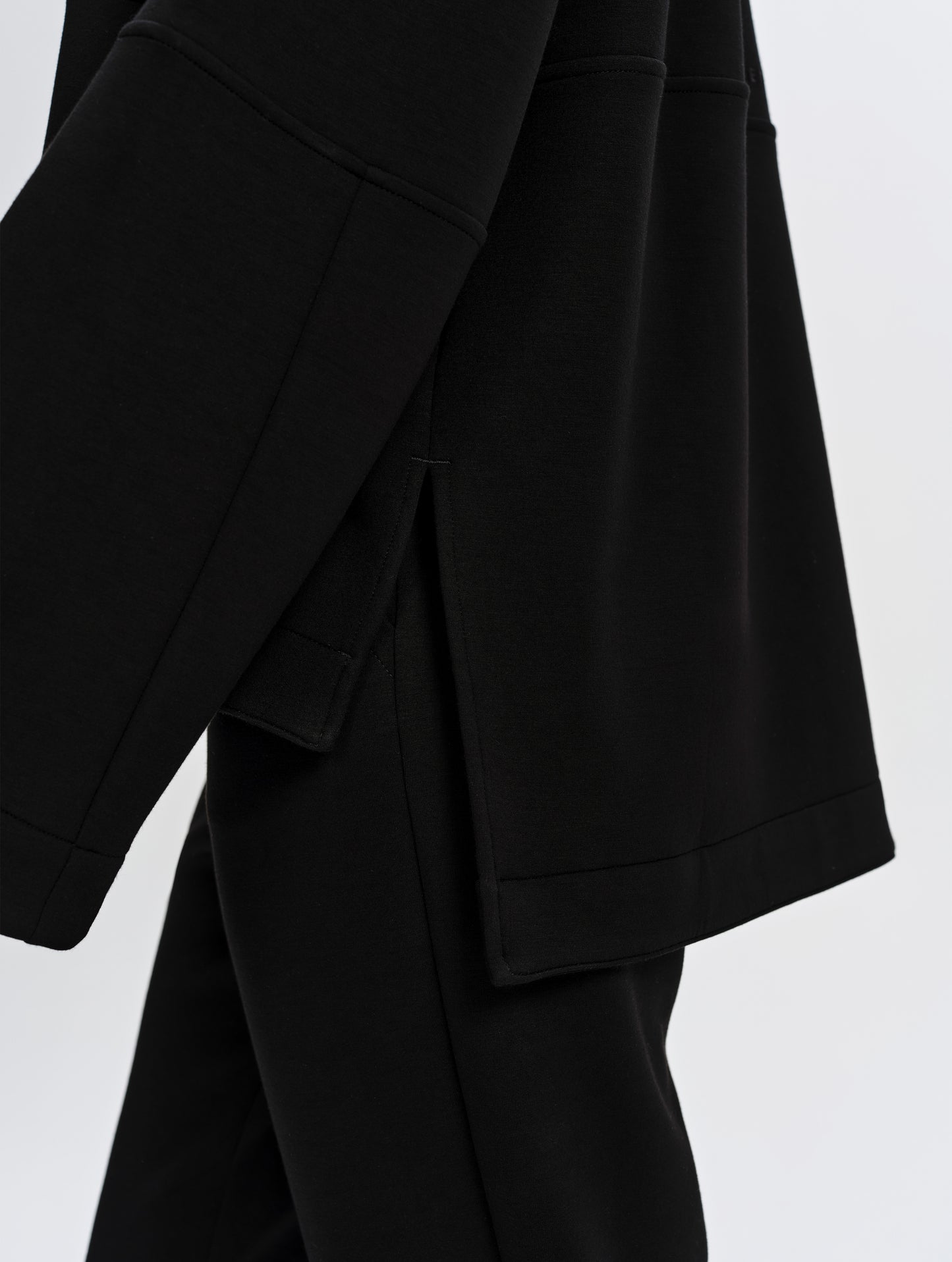 Closeup detailed view of the hem side slits and oversized cuffs on the Blaire Premium Hoodie in Onyx Black from AETHER Apparel.