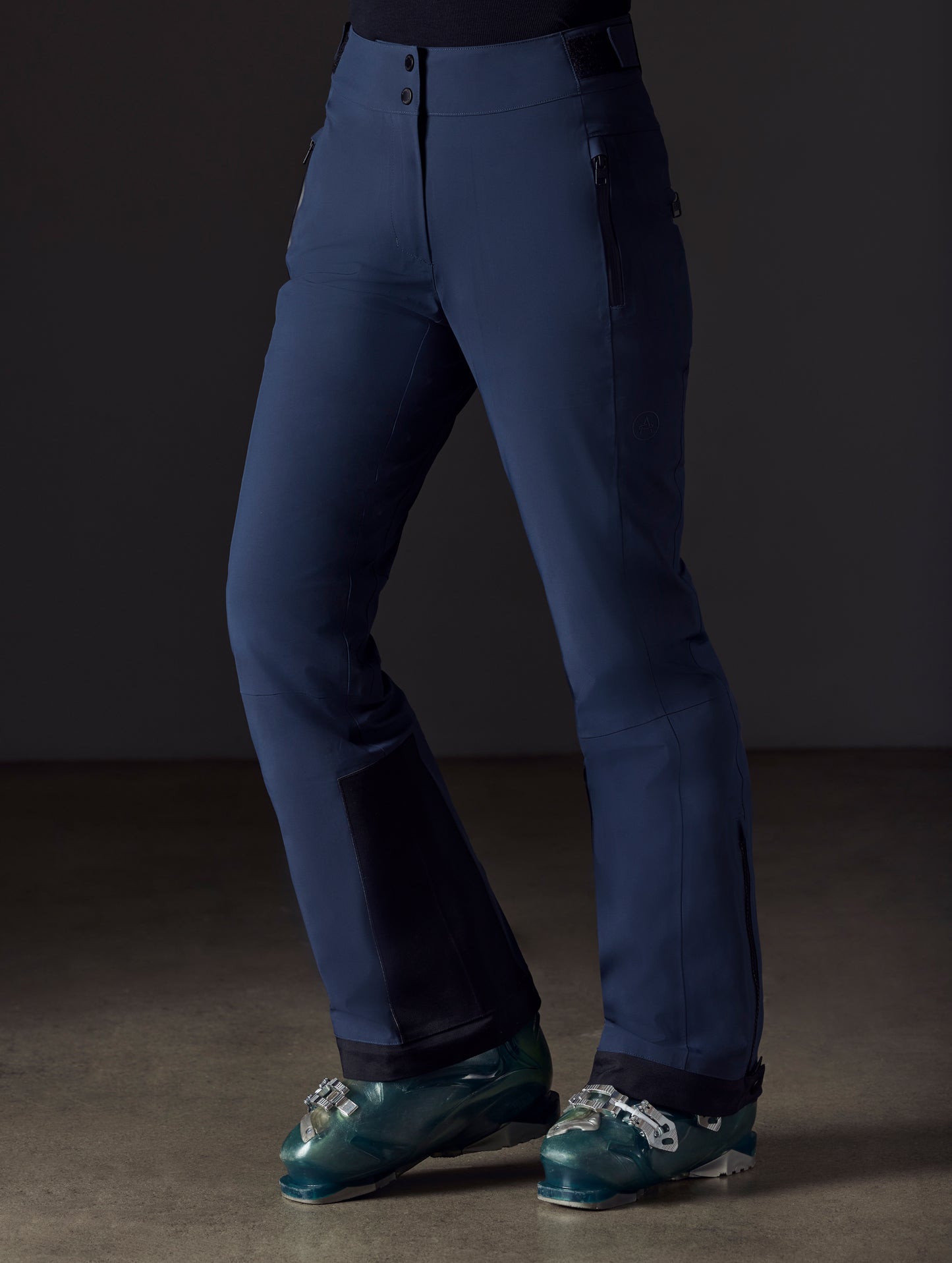 Front left angled lower body view of woman wearing Boyd Snow Pant in Total Eclipse dark blue from AETHER Apparel.