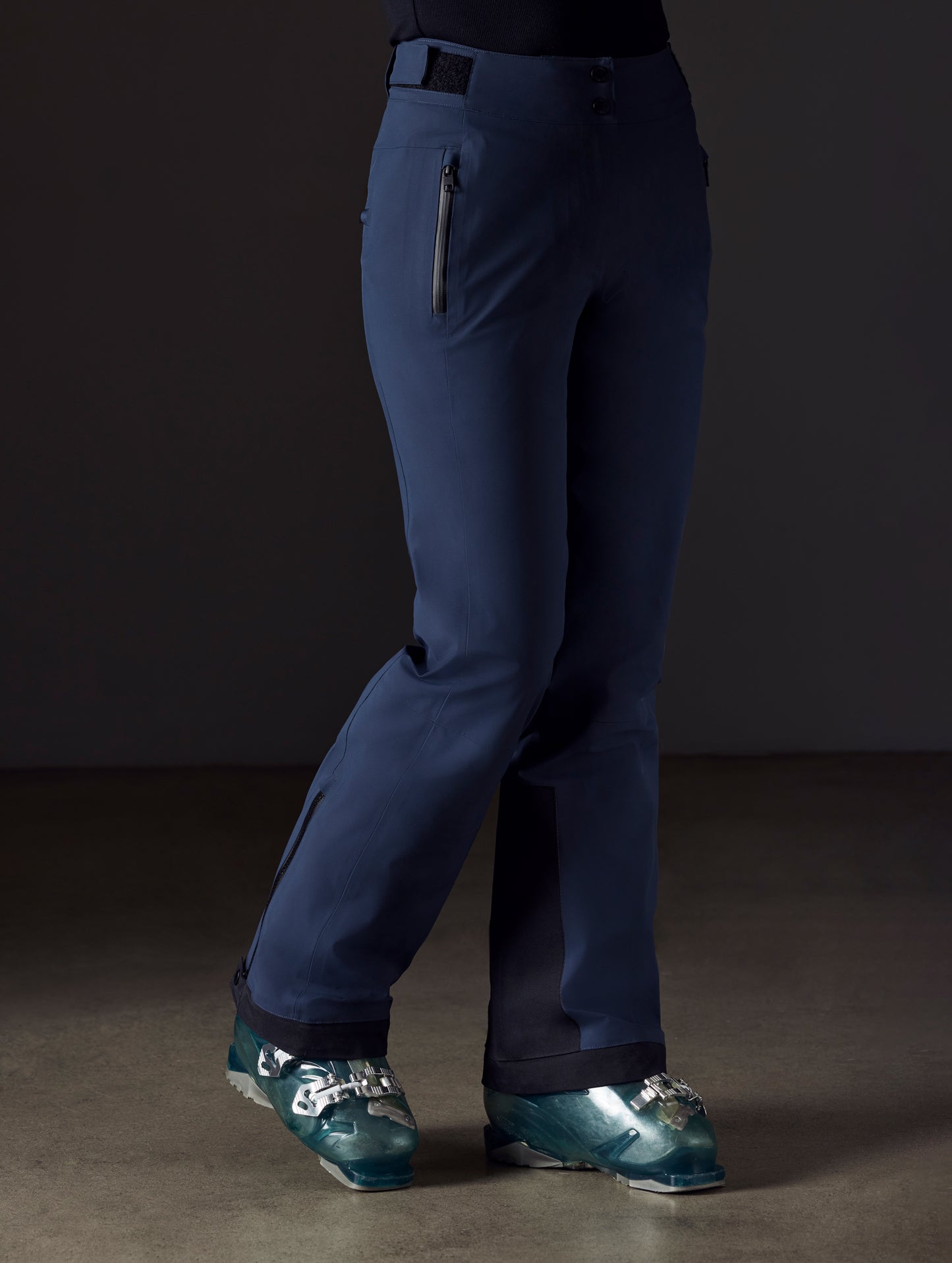 Front right angled lower body view of woman wearing Boyd Snow Pant in Total Eclipse dark blue from AETHER Apparel.