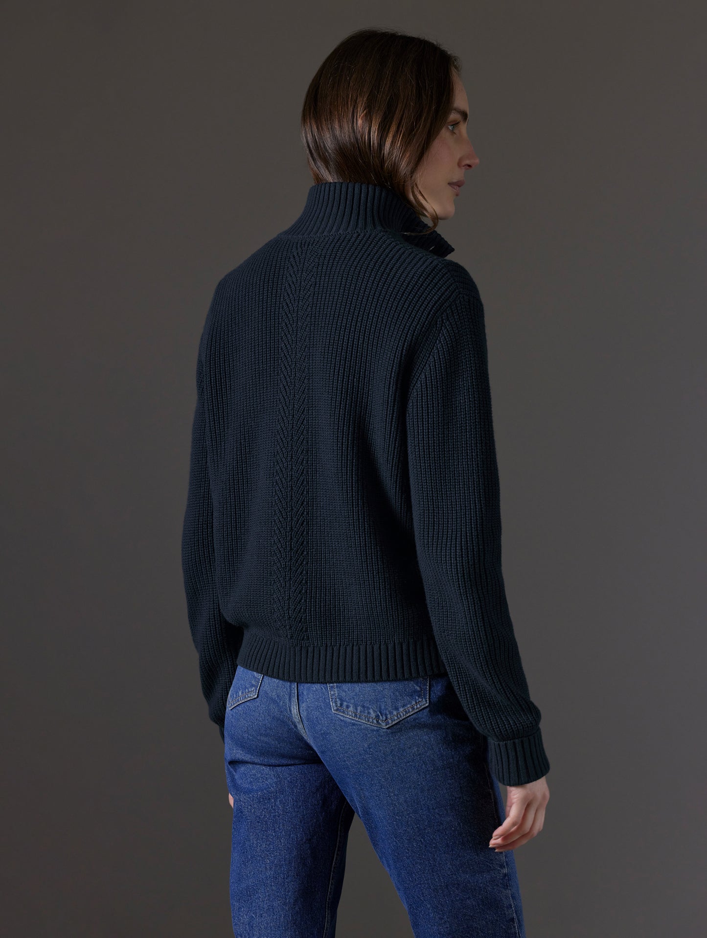 Rear angled view of woman wearing Cato Buttoned Sweater in Total Eclipse dark blue from AETHER Apparel.