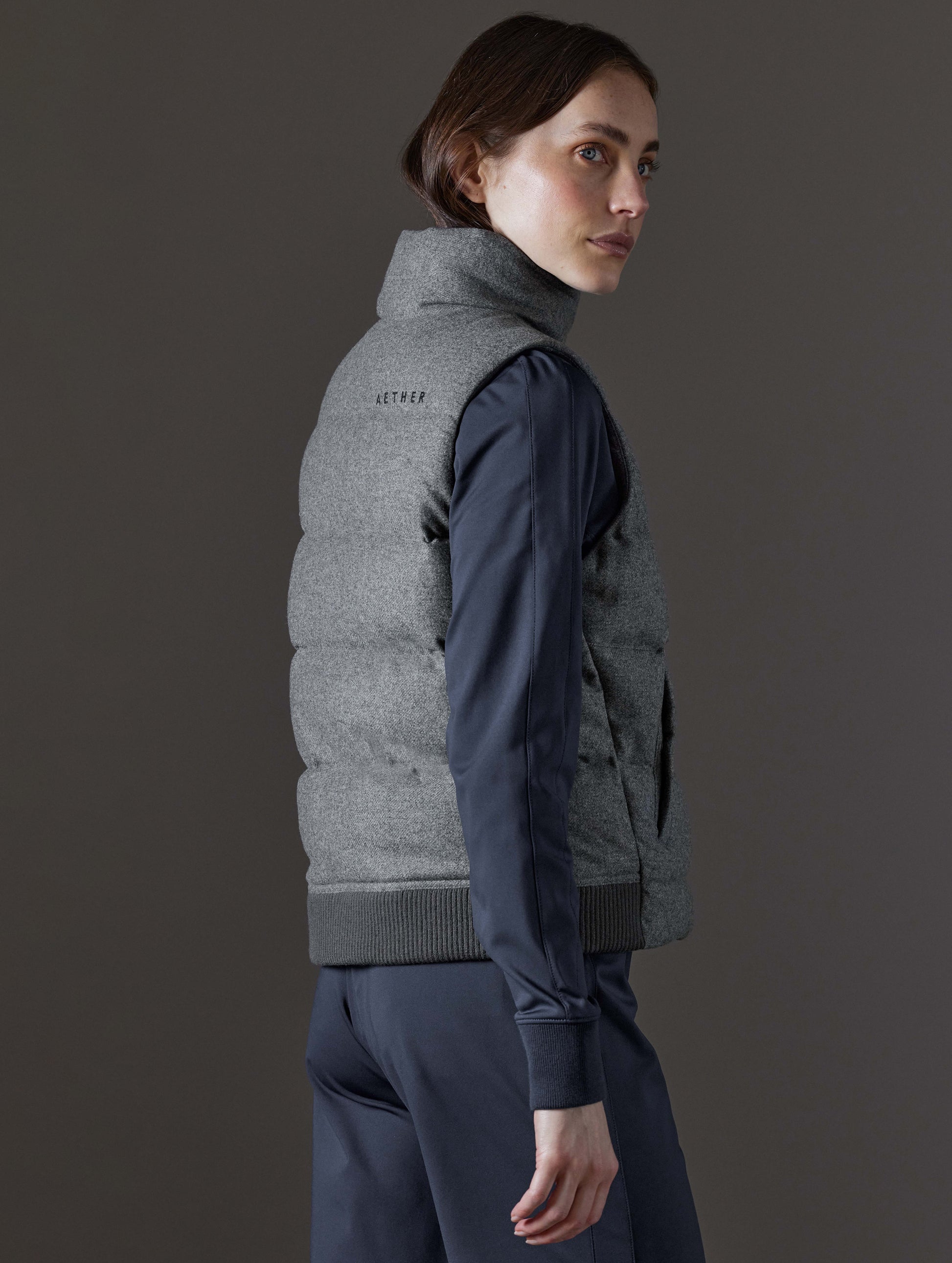 Rear angled view of woman wearing Channing Vest 2.0 in Heather Grey from AETHER Apparel.