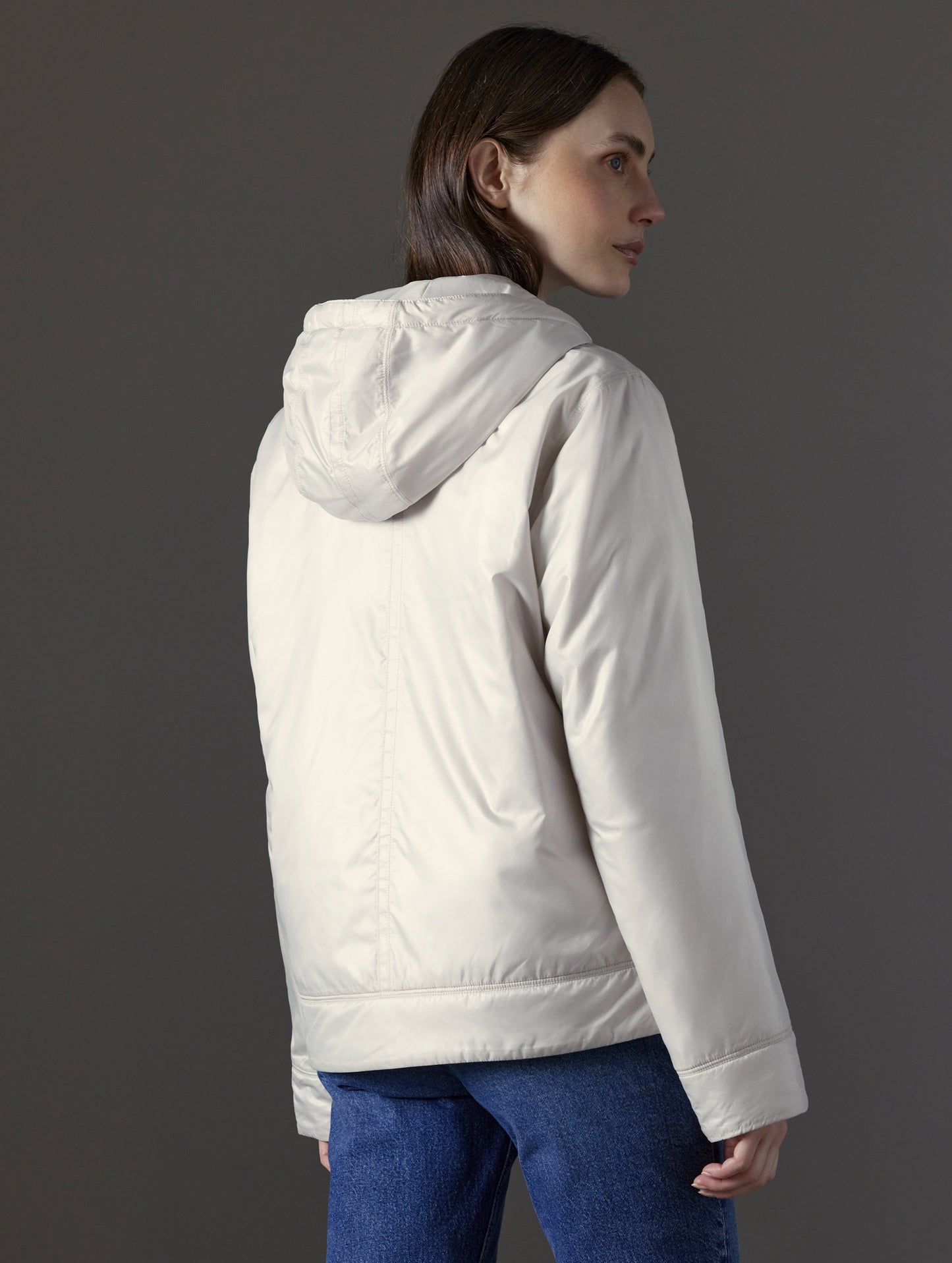 Rear angled view of woman wearing Eco Space Hoodie in Bone white from AETHER Apparel.