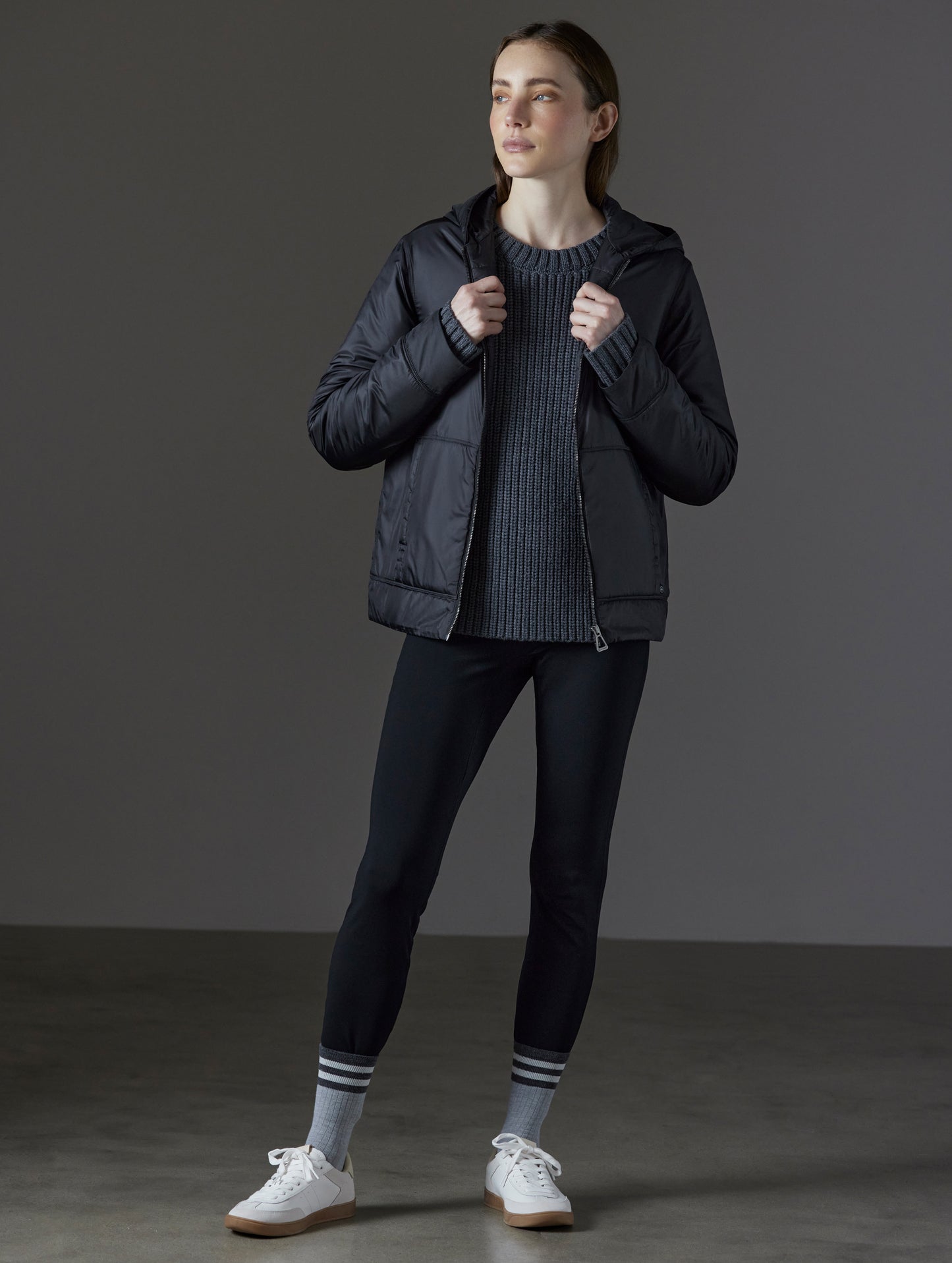 Front angled full-body view of woman wearing Eco Space Hoodie in Onyx Black from AETHER Apparel.