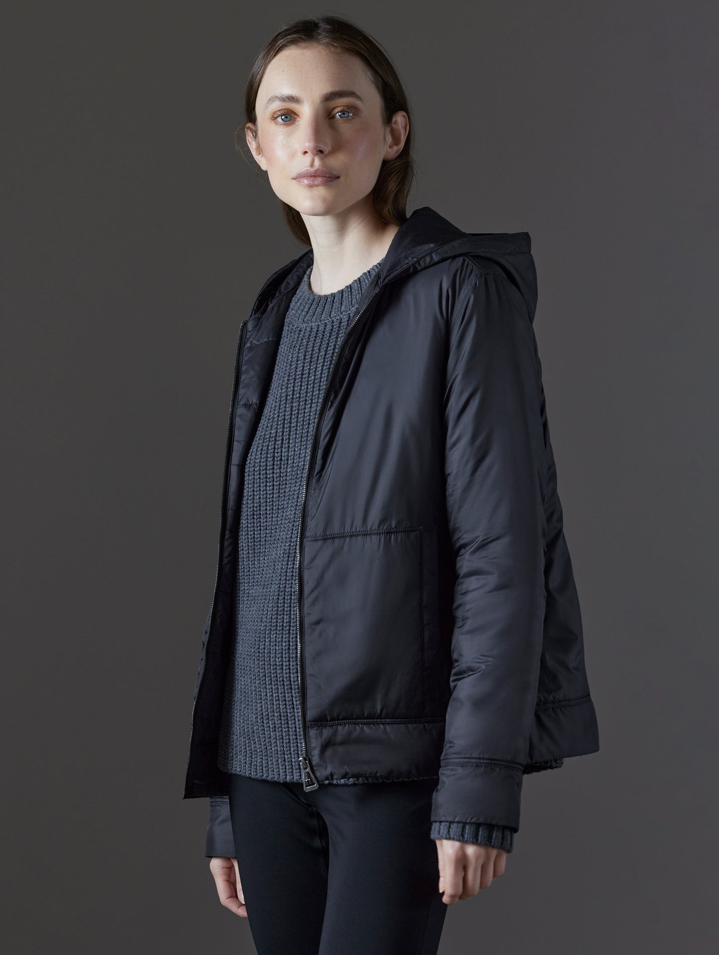 Front angled view of woman wearing unzipped Eco Space Hoodie in Onyx Black from AETHER Apparel.