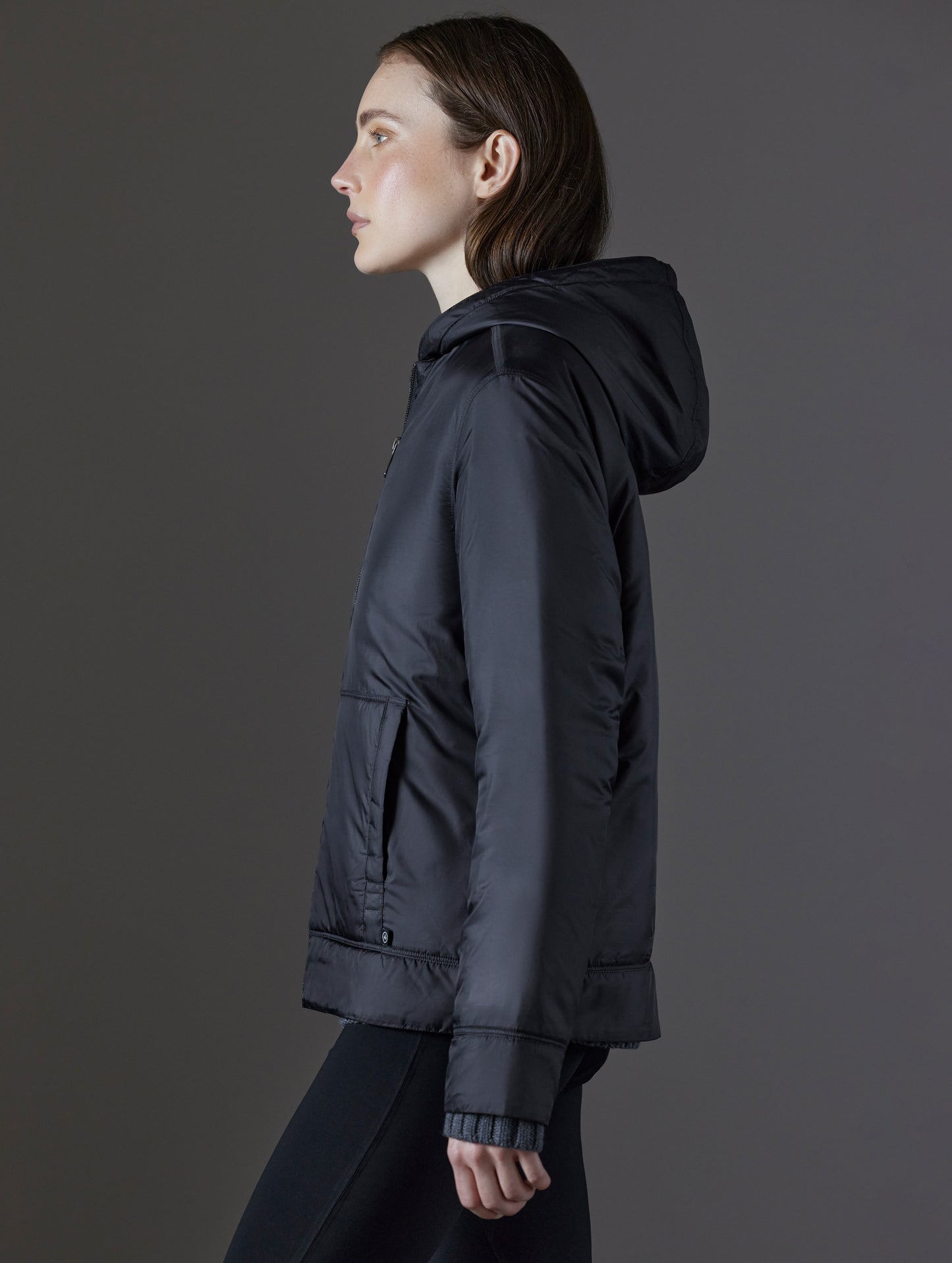 Side profile view of woman wearing Eco Space Hoodie in Onyx Black from AETHER Apparel.