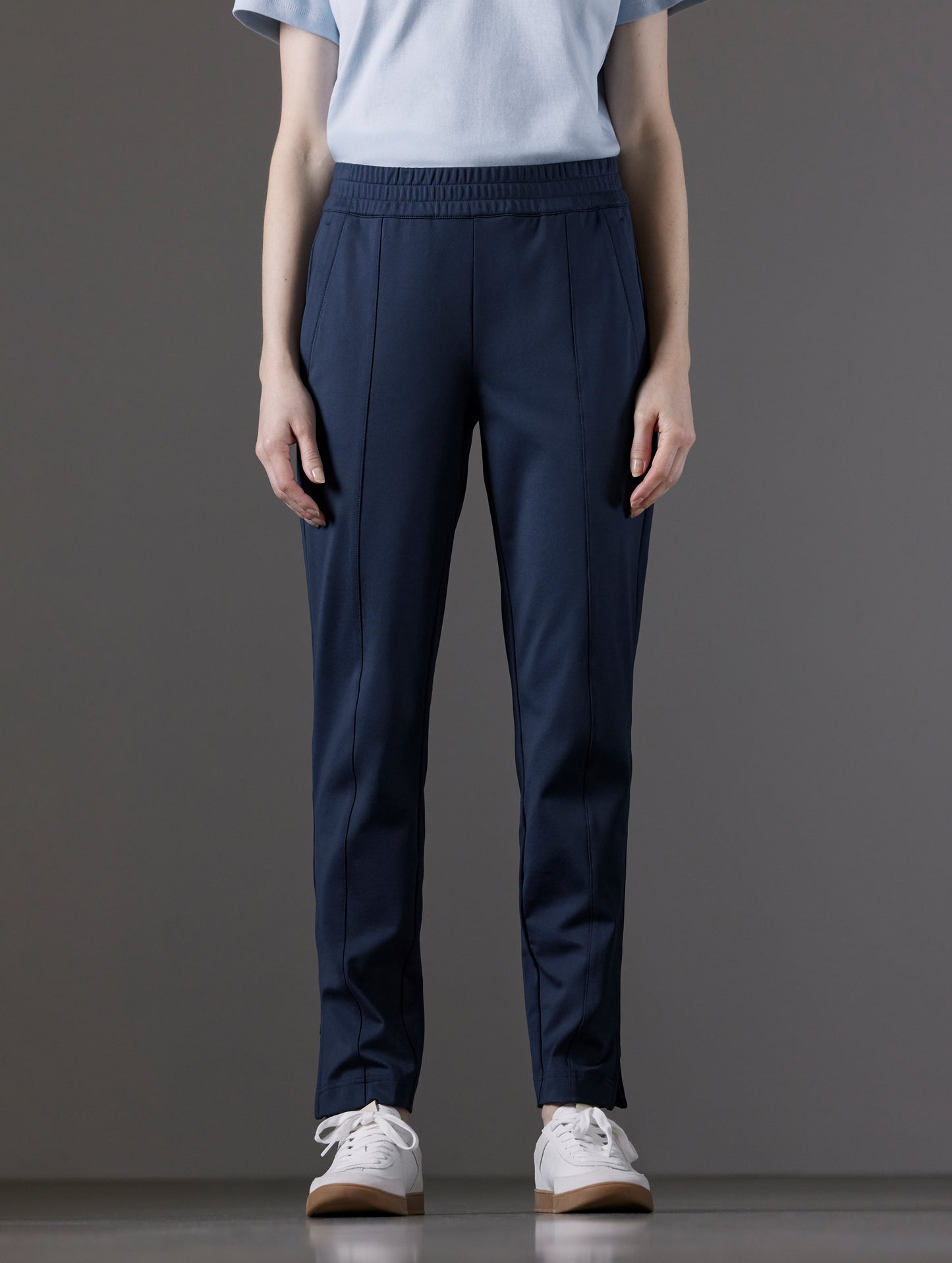 Front lower body view of woman wearing Eloise Travel Slim Pant in Total Eclipse dark blue from AETHER Apparel.