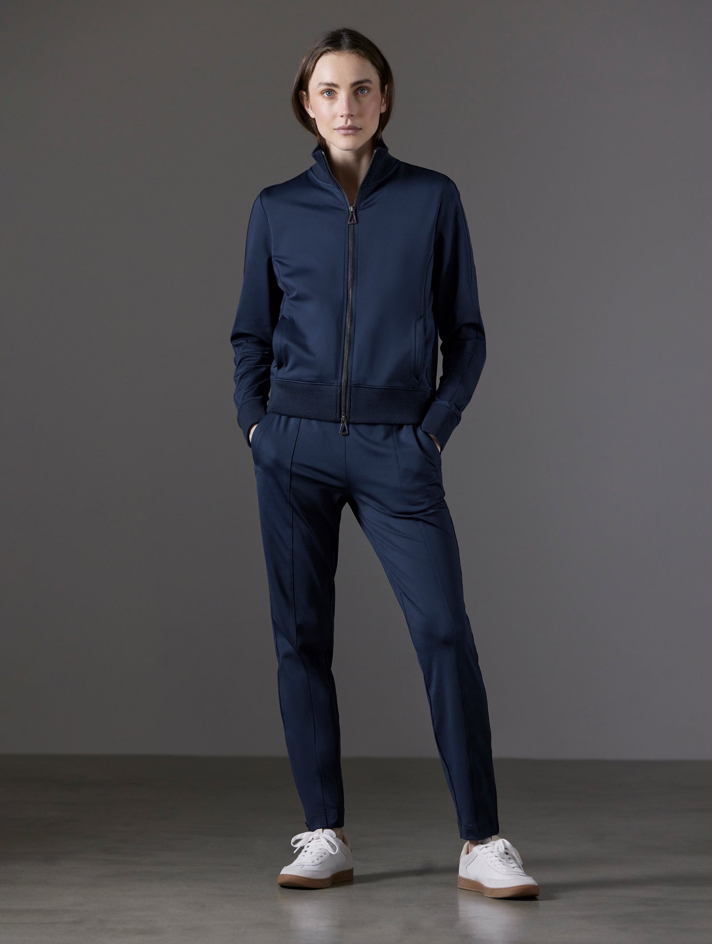 Front full-body view of woman wearing Eloise Travel Slim Pant in Total Eclipse dark blue from AETHER Apparel.