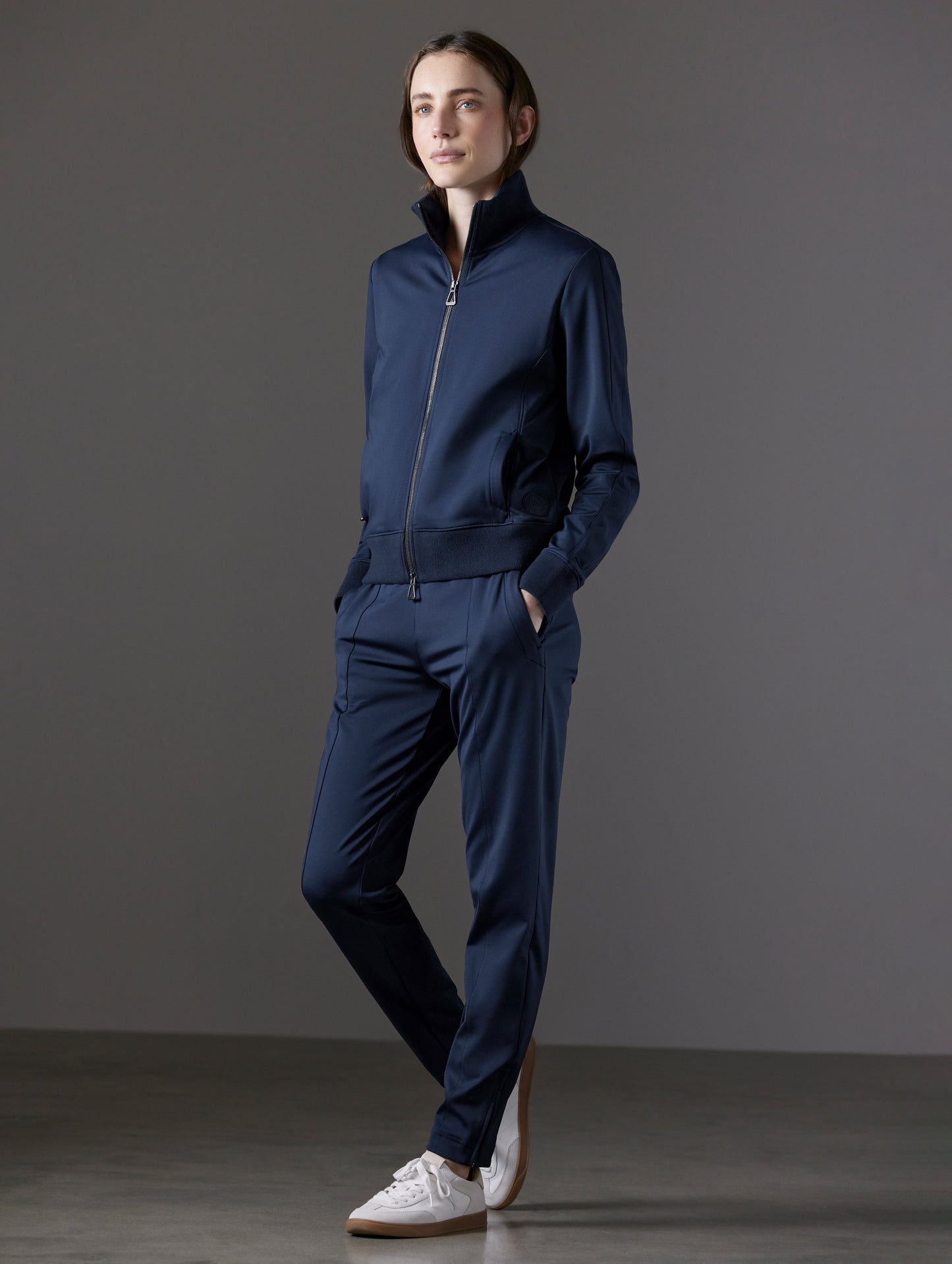 Front angled full-body view of woman wearing Eloise Travel Slim Pant in Total Eclipse dark blue from AETHER Apparel.