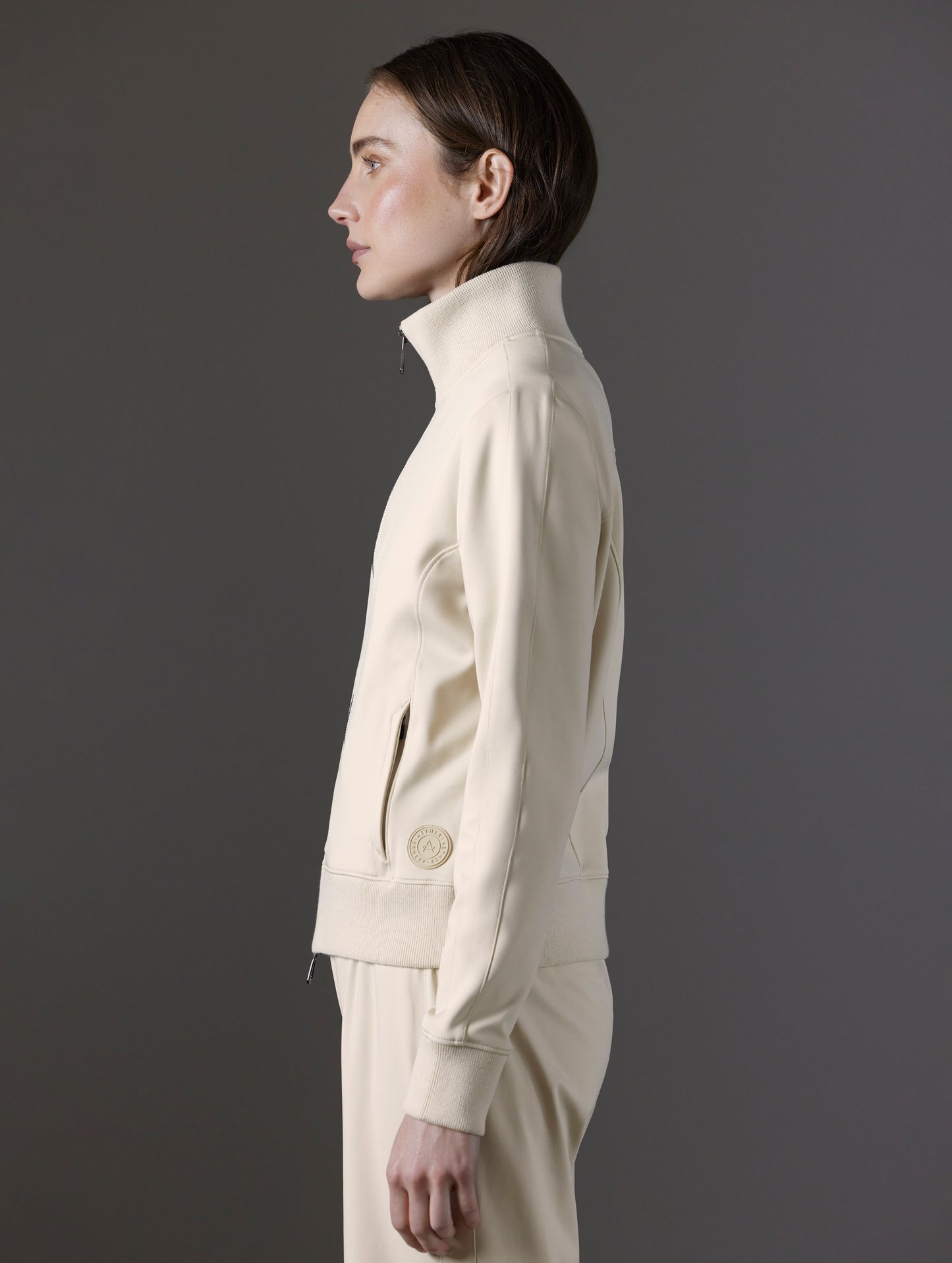 Side profile view of woman wearing Eloise Travel Jacket in Bone white from AETHER Apparel.