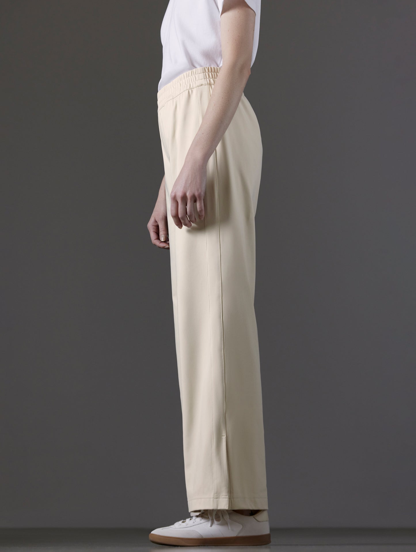 Side profile lower body view of woman wearing Eloise Travel Slim Pant in Bone white from AETHER Apparel.