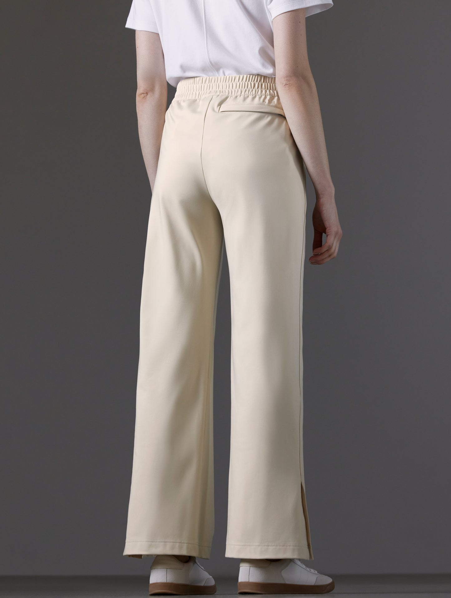 Rear angled lower body view of woman wearing Eloise Travel Slim Pant in Bone white from AETHER Apparel.
