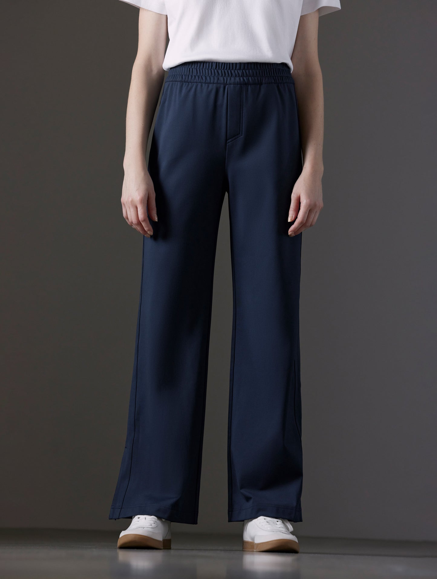 Front lower body view of woman wearing Eloise Travel Slim Pant in Total Eclipse dark blue from AETHER Apparel.
