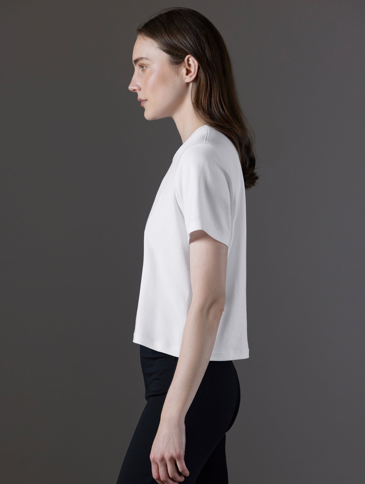 Side profile view of woman wearing Emery Pima Cropped Tee in White from AETHER Apparel.