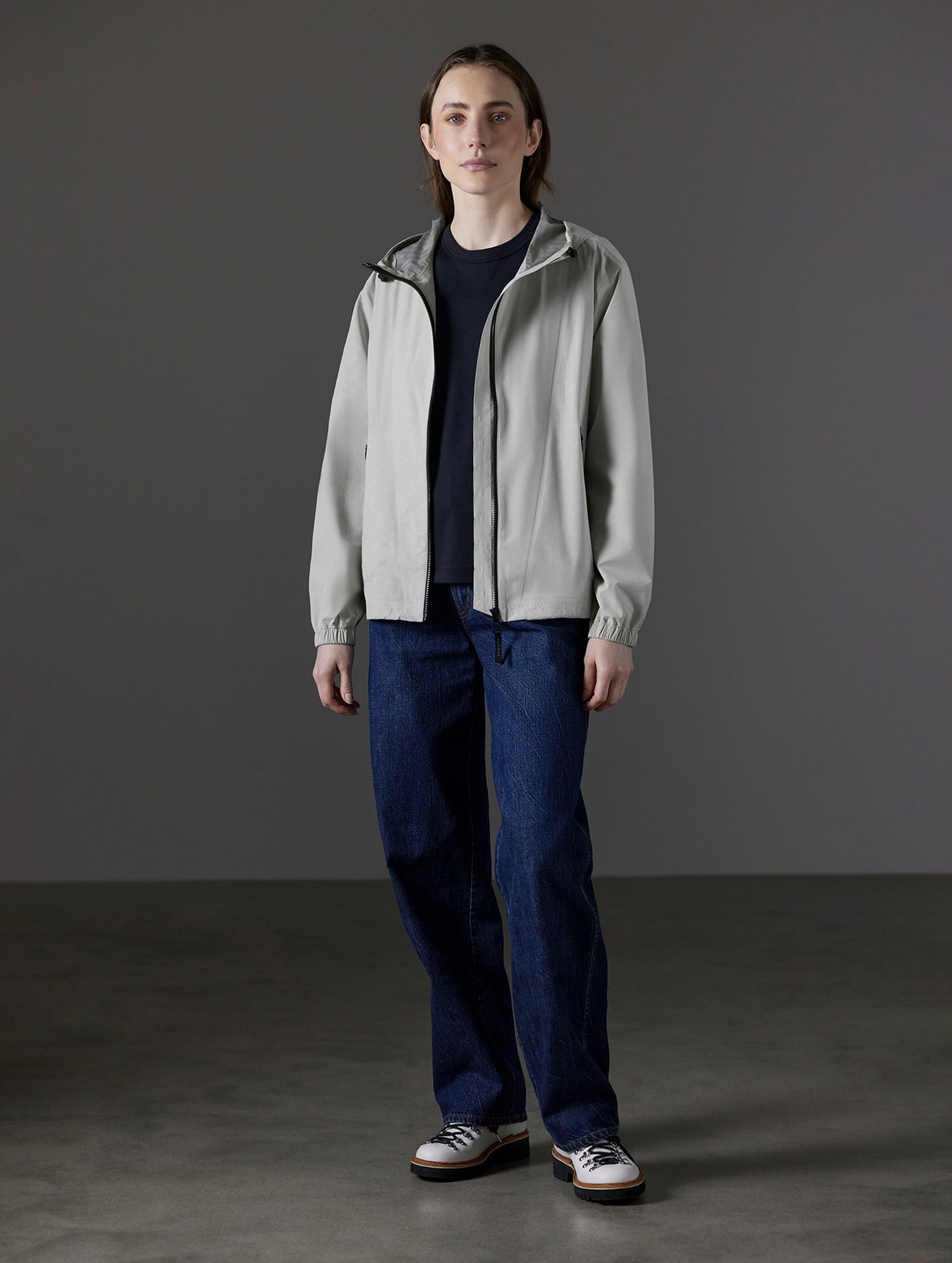 Front full-body view of woman wearing Kite Lightweight Jacket in Stone Grey from AETHER Apparel.