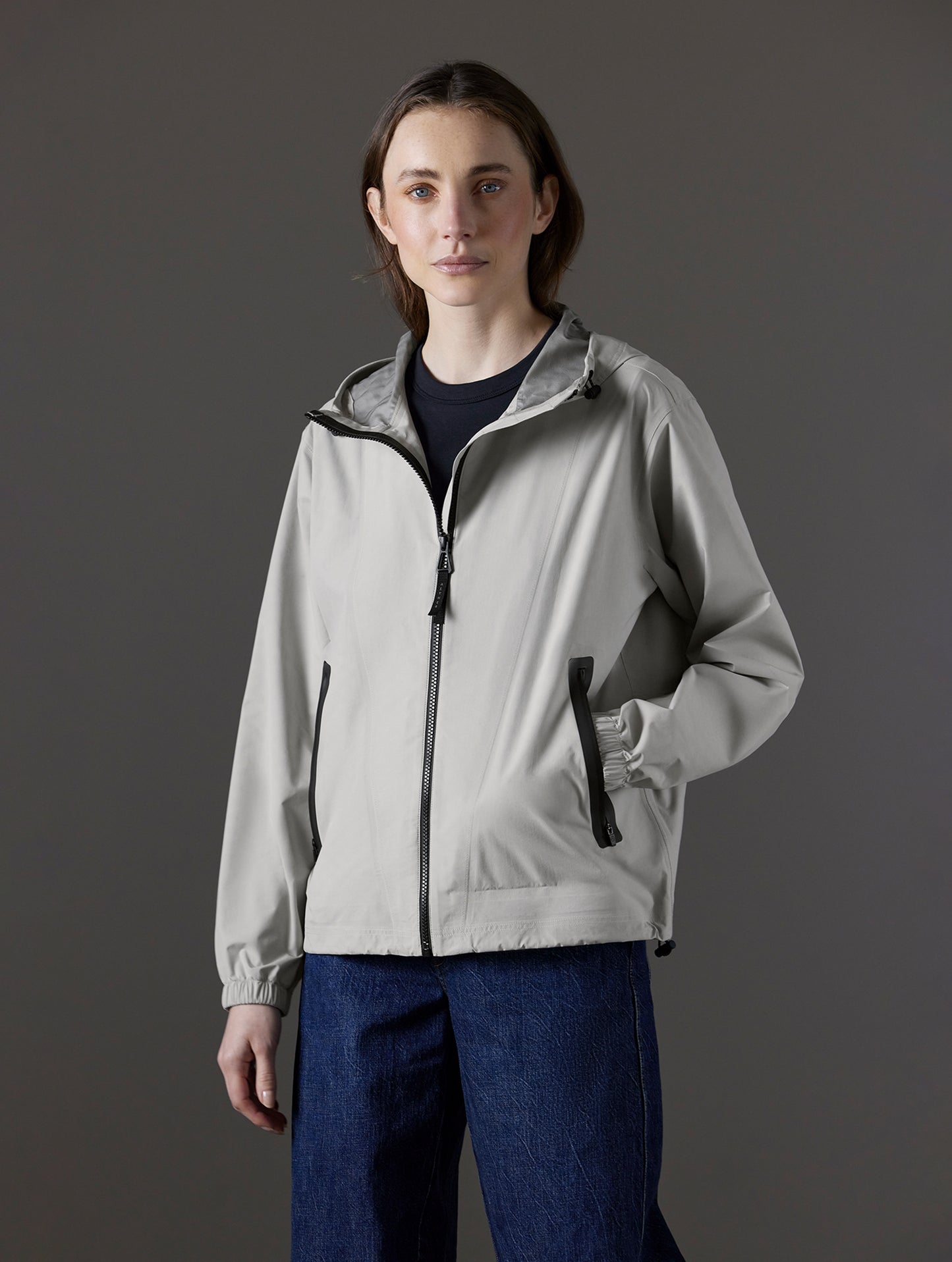 Front angled body view of woman wearing Kite Lightweight Jacket in Stone Grey from AETHER Apparel.