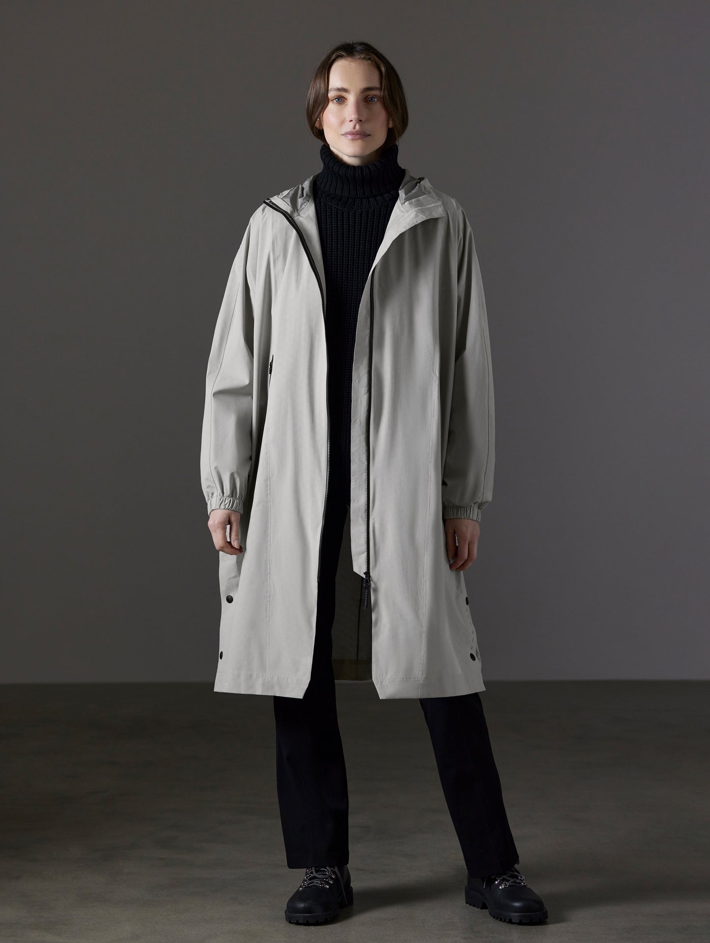 Front full-body view of woman wearing Kite Packable Rain Poncho in Stone Grey from AETHER Apparel.