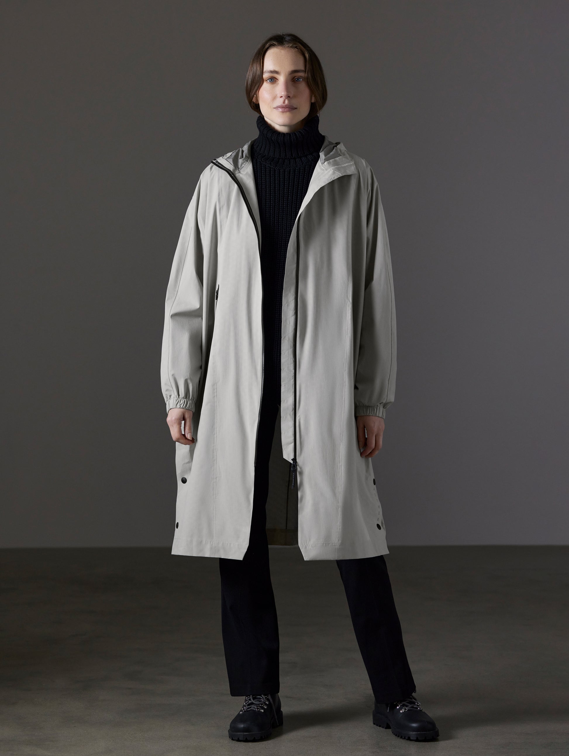 Front full-body view of woman wearing Kite Packable Rain Poncho in Stone Grey from AETHER Apparel.