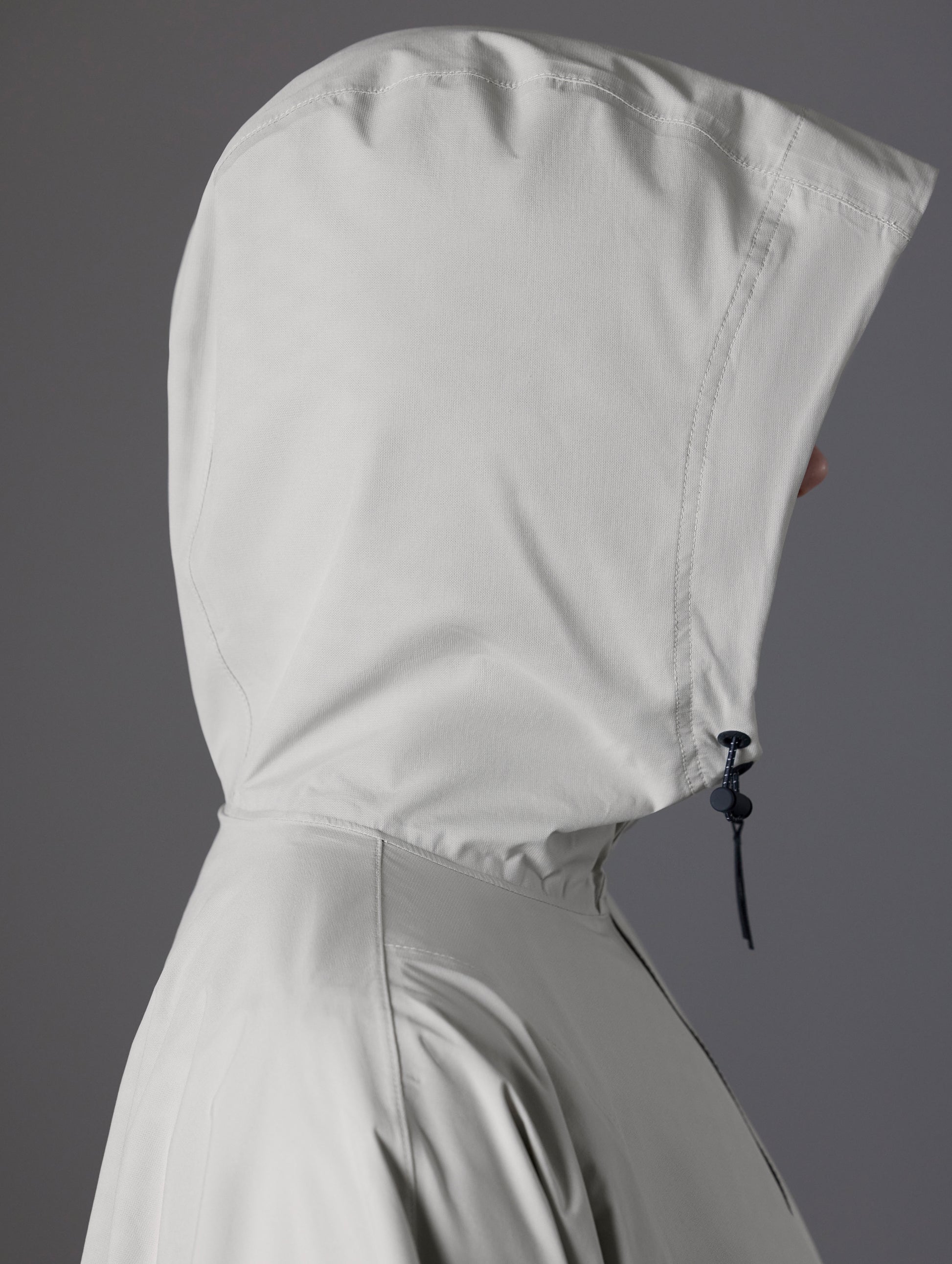 Side profile view of the three-piece hood on the Kite Packable Rain Poncho in Stone Grey from AETHER Apparel.
