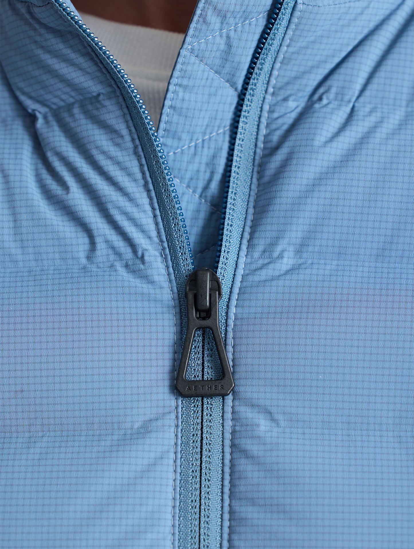 Closeup detail view of center front zipper of W Launch Full-Zip Jacket NH in Portal Blue from AETHER Apparel.