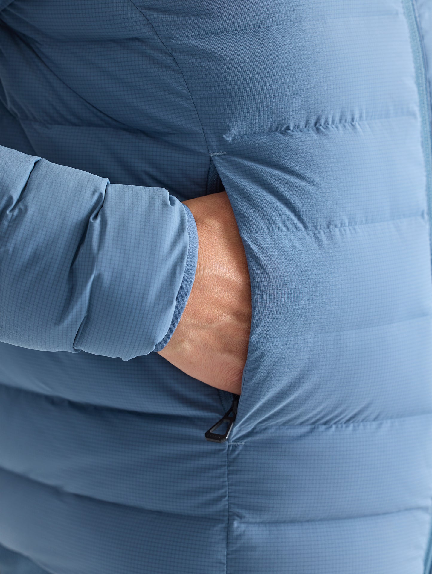 Closeup detail view of wearer's hand in right pocket of W Launch Full-Zip Jacket NH in Portal Blue from AETHER Apparel.